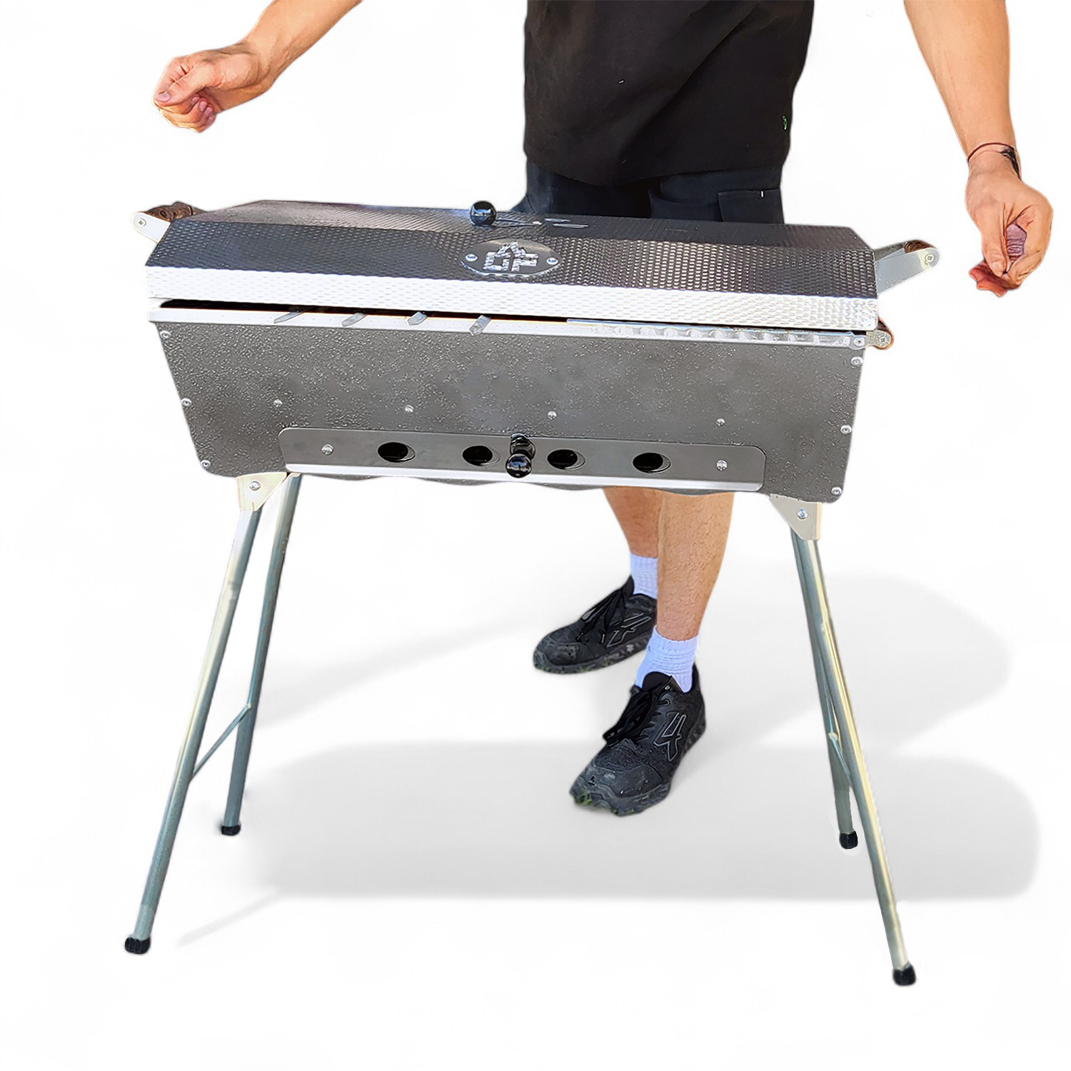 Eine Person öffnet einen tragbaren Grill auf weißem Hintergrund.