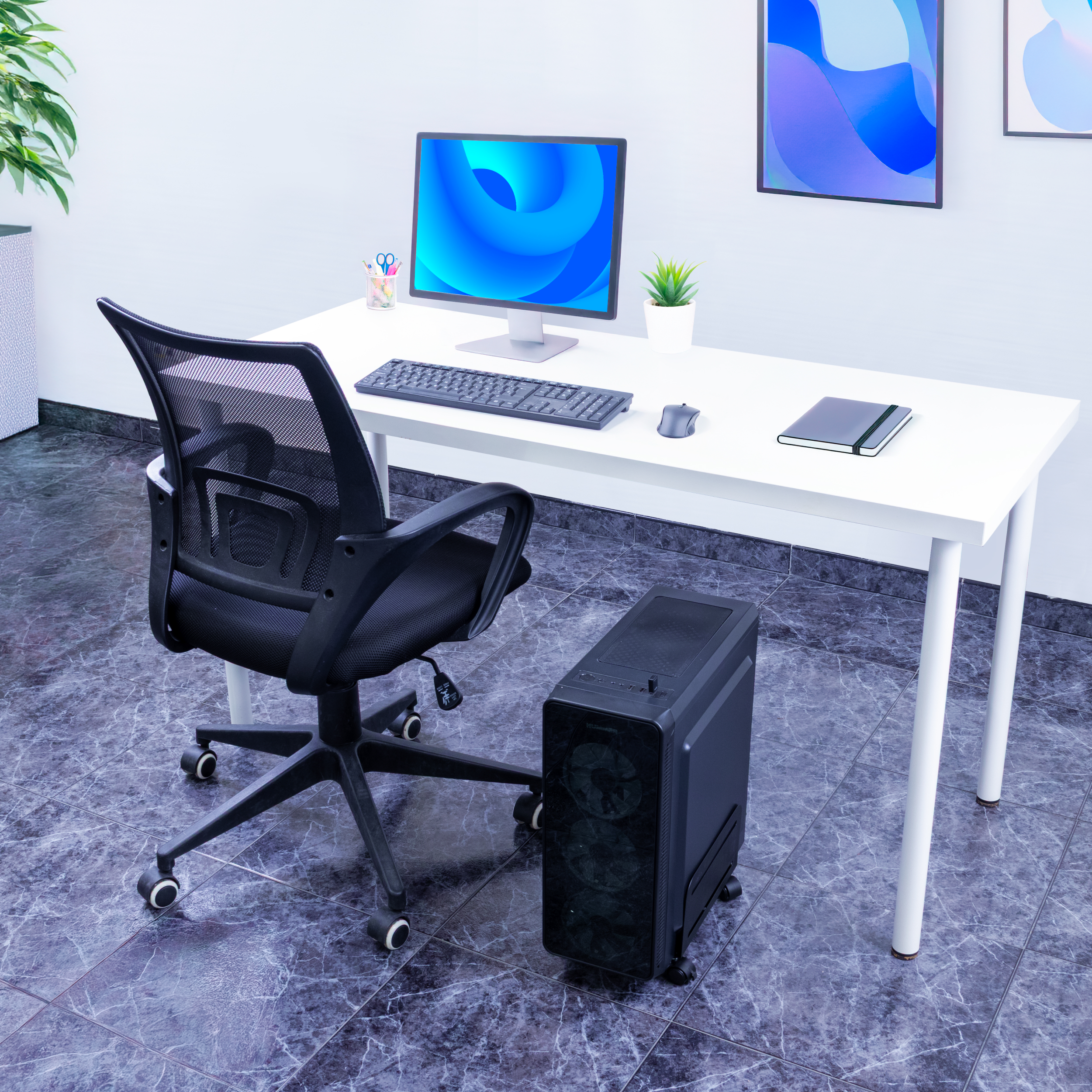 Escritorio con ordenador, teclado, ratón y silla negra. Una torre de PC en el suelo. Paredes y suelo blancos.