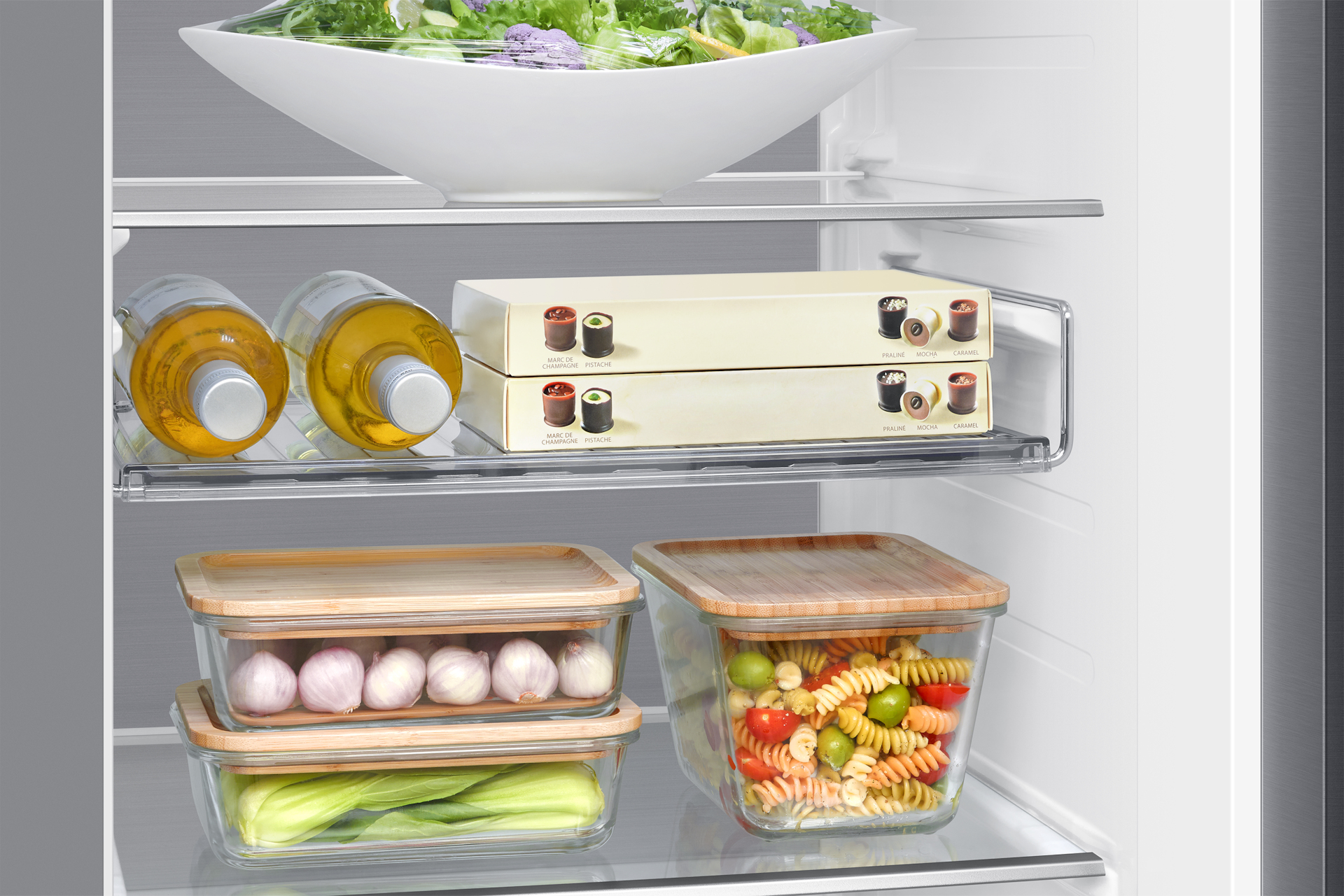 Zbliżenie na uporządkowane półki lodówki z pojemnikami i butelkami, pokazujące przechowywanie żywności.