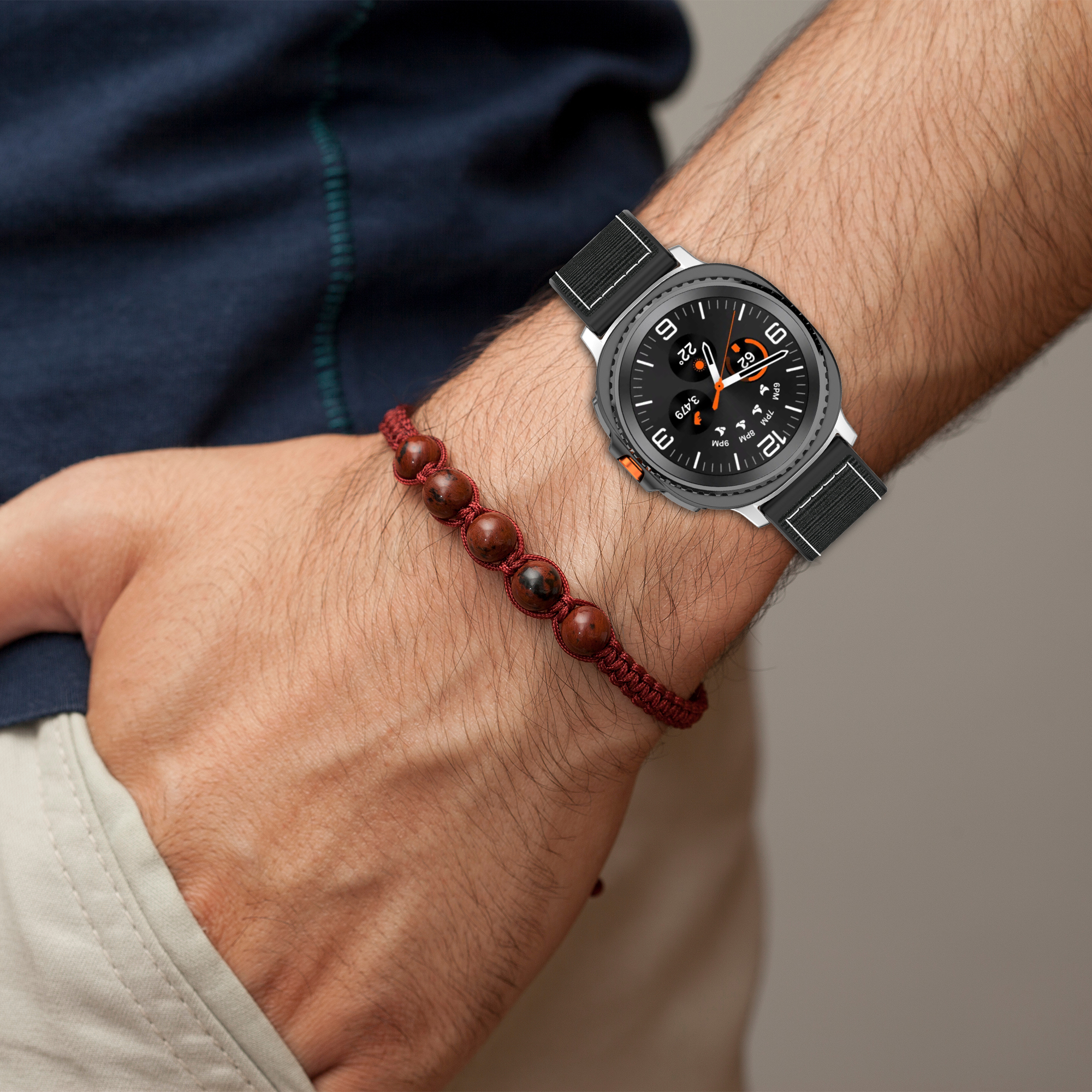 Das Handgelenk einer Person mit einer Smartwatch und einem roten Perlenarmband.