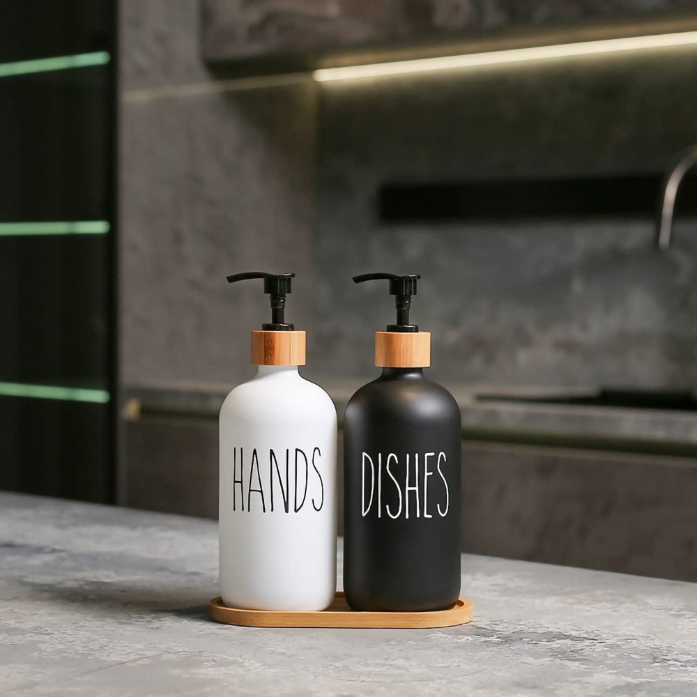 Zwei Seifenspender mit der Aufschrift "HANDS" und "DISHES" auf einem Holztablett.