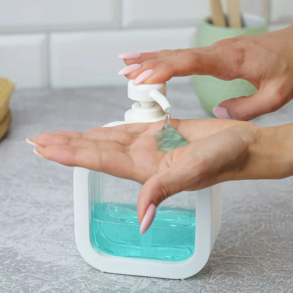 Eine Hand gibt blaue Flüssigseife aus einem weißen, quadratischen Seifenspender in eine Handfläche ab.