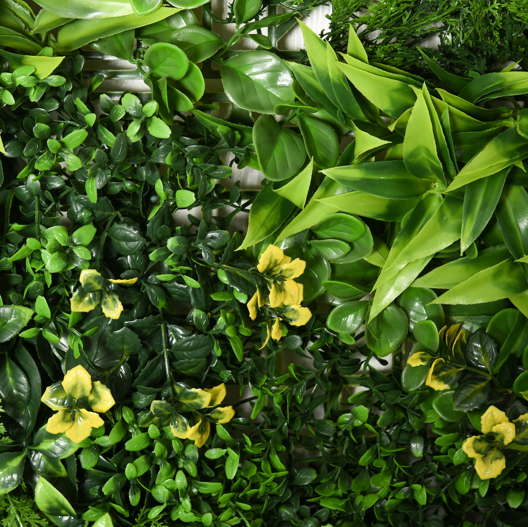 Nahaufnahme von künstlichen grünen Pflanzen mit gelben Blüten. Die Pflanzen sind dicht beieinander.