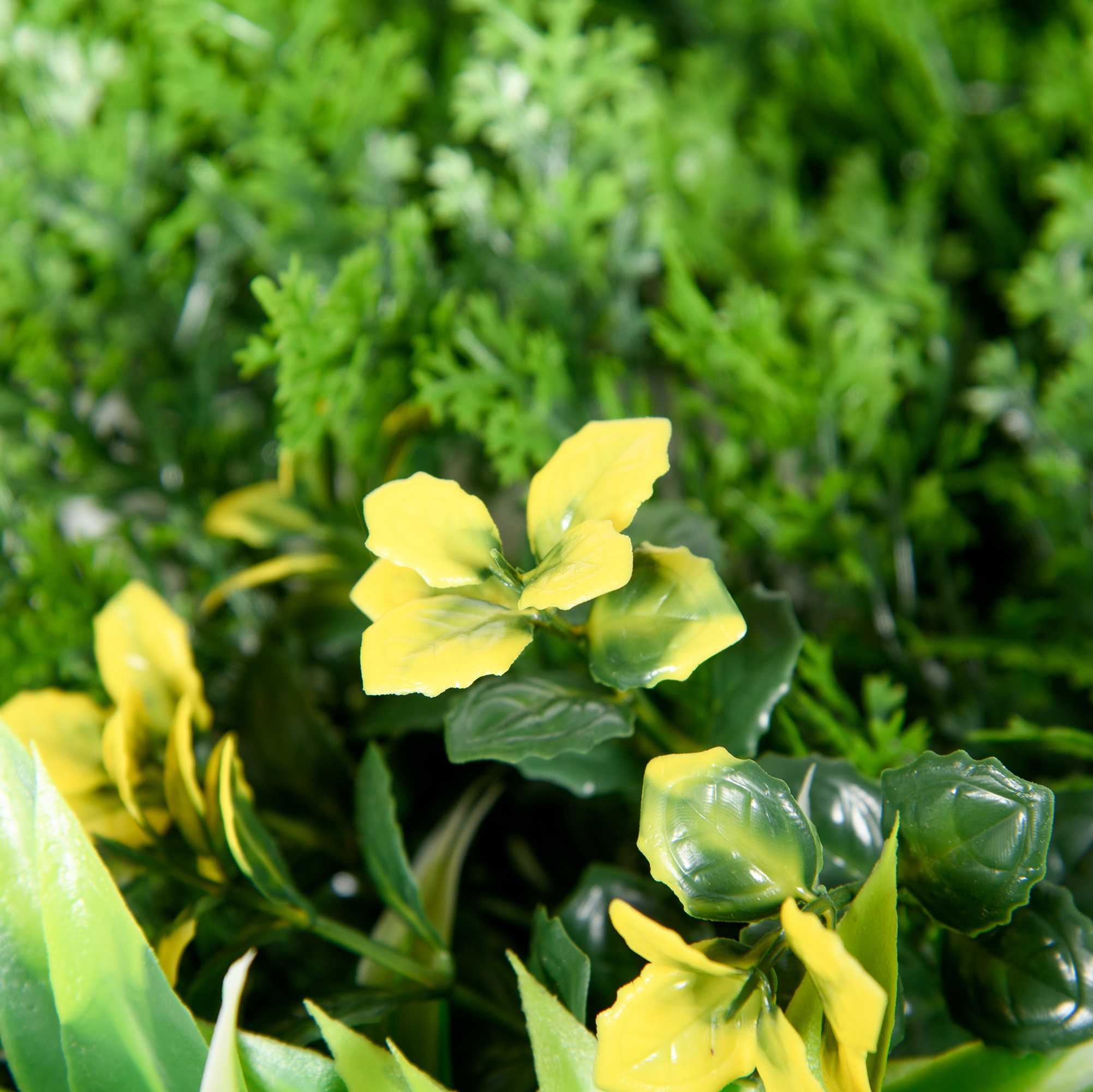 Nahaufnahme von gelben und grünen künstlichen Pflanzenblüten und -blättern.