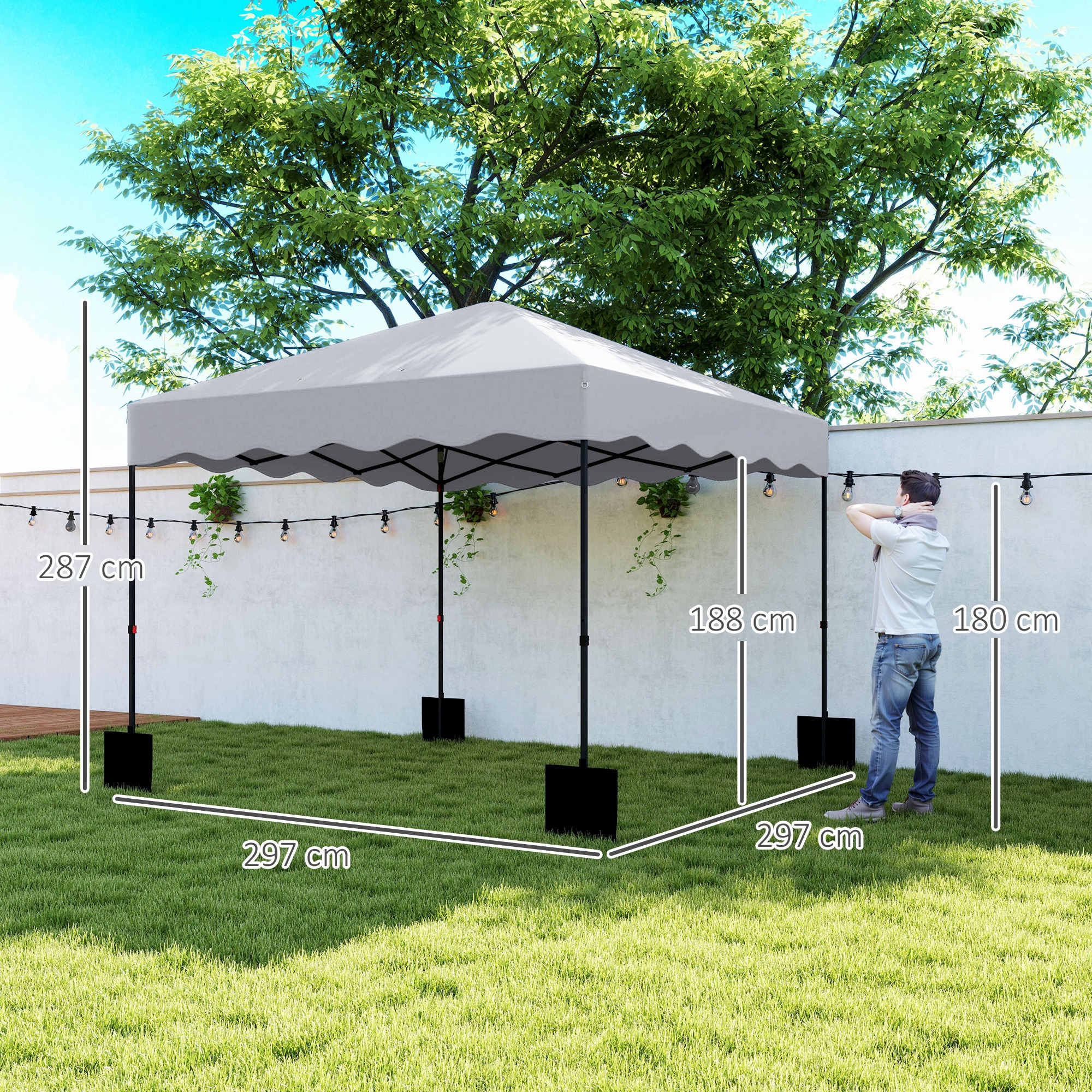 Ein grauer Pavillon steht auf einem Rasen mit markierten Abmessungen; eine Person passt in der Nähe Lichterketten an.