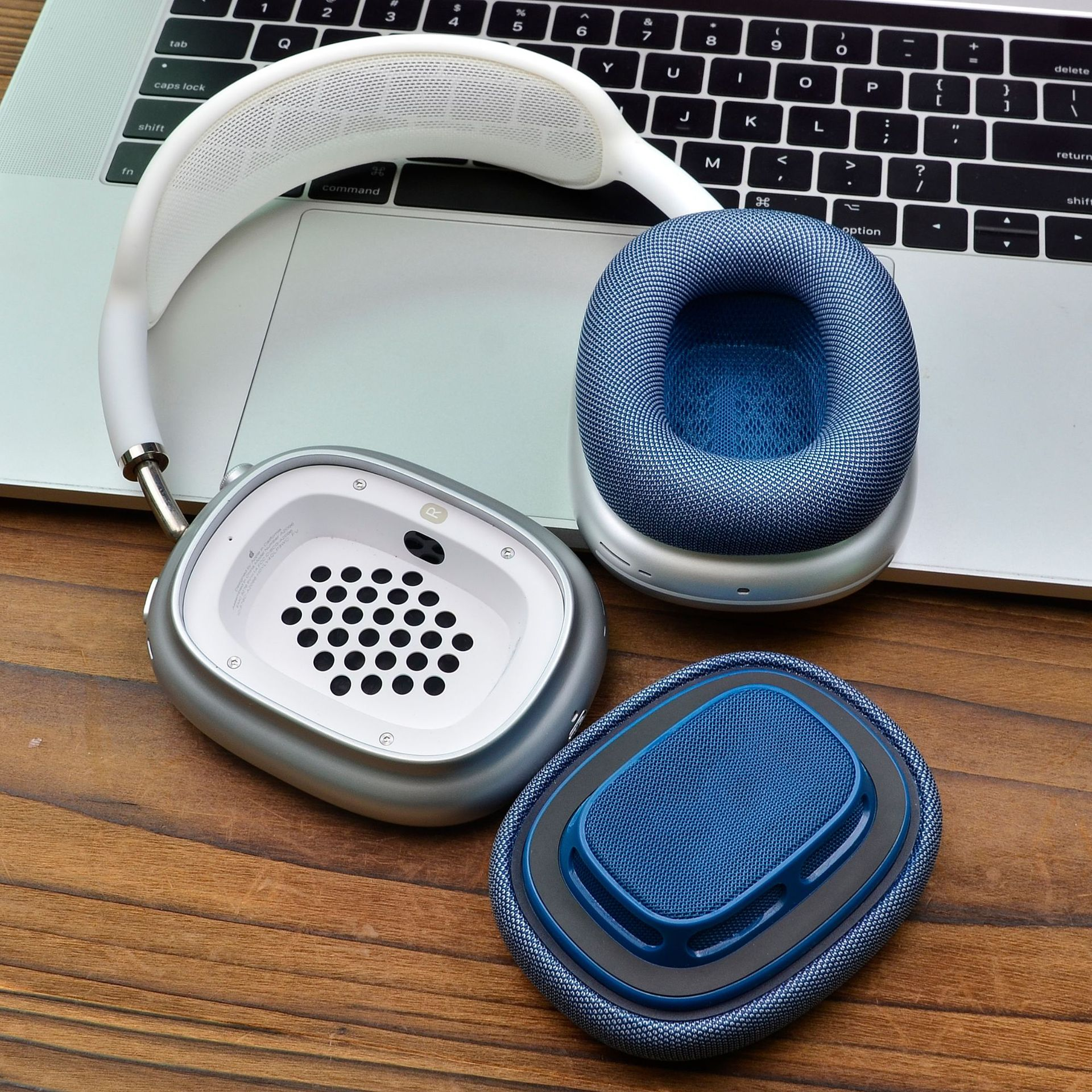Cuffie, con fascia bianca, padiglioni argentati e cuscinetti blu, su superficie in legno.