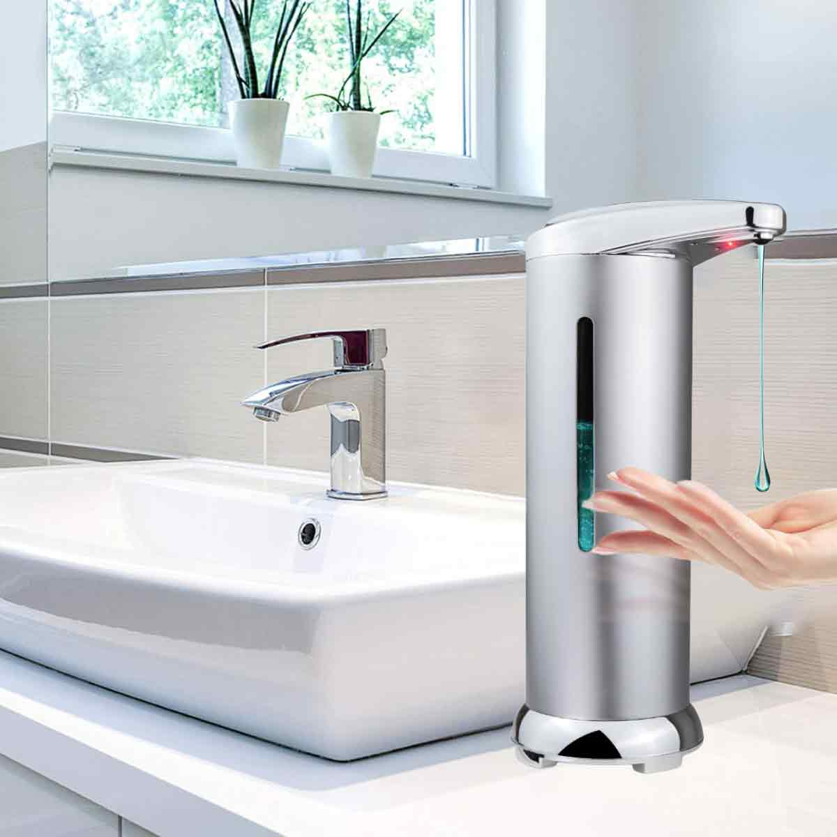 Ein silberner Seifenspender neben einem Waschbecken, eine Hand fängt Seife auf.