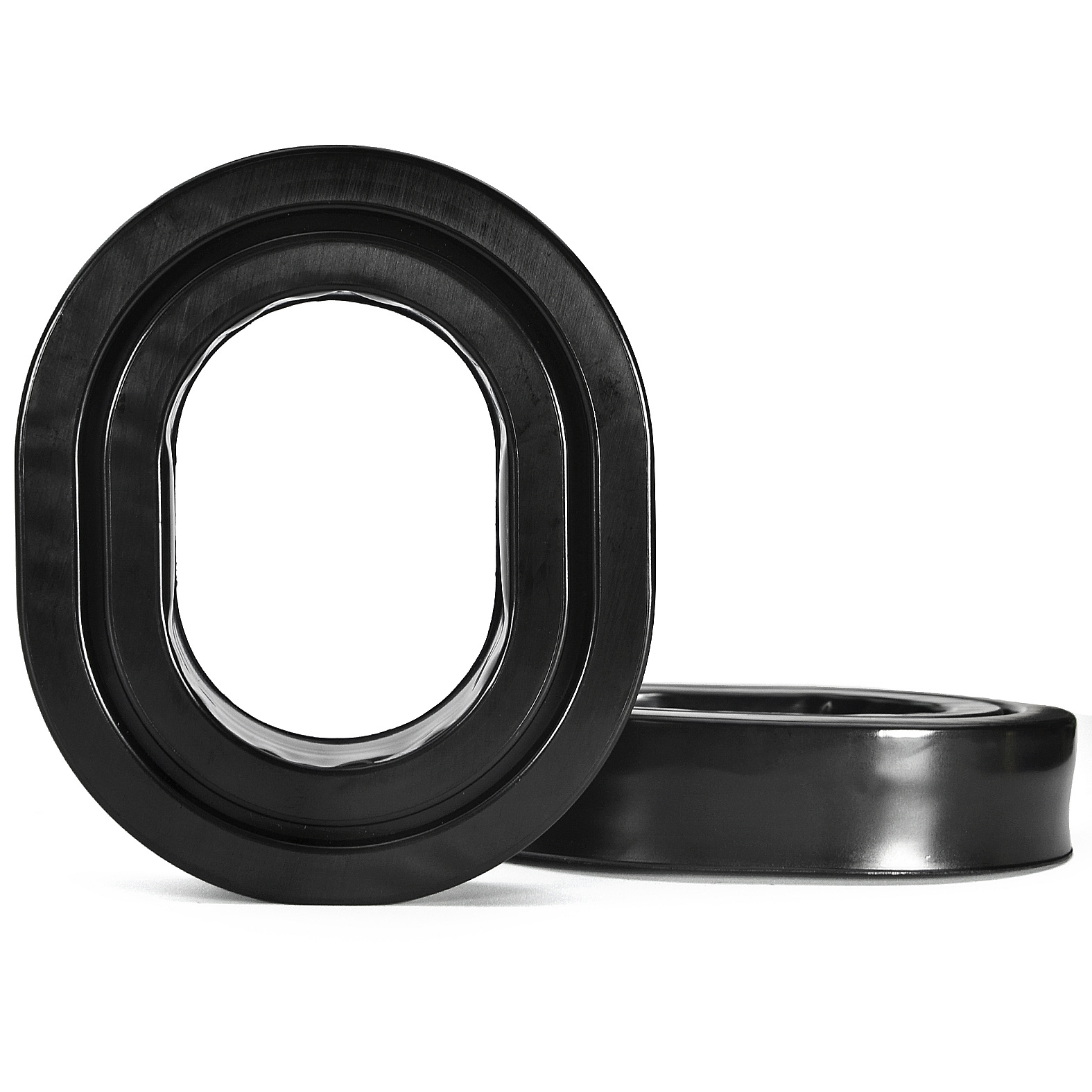 Due inserti in schiuma neri a forma ovale, forse per cuffie, su sfondo bianco. Uno ha una base piatta.