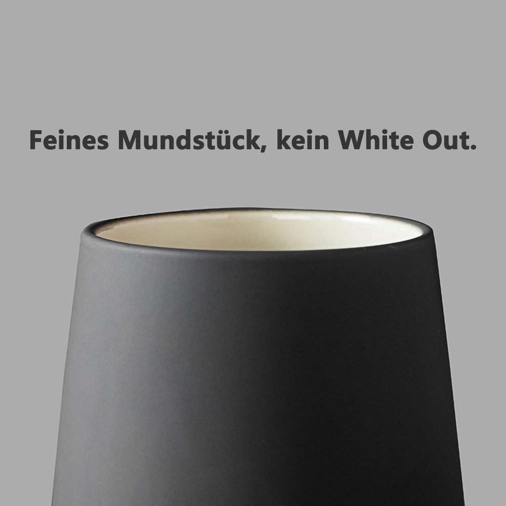 Ein schwarzes Glas mit der Oberseite des Glases im Blick. Das Glas befindet sich auf grauem Hintergrund.