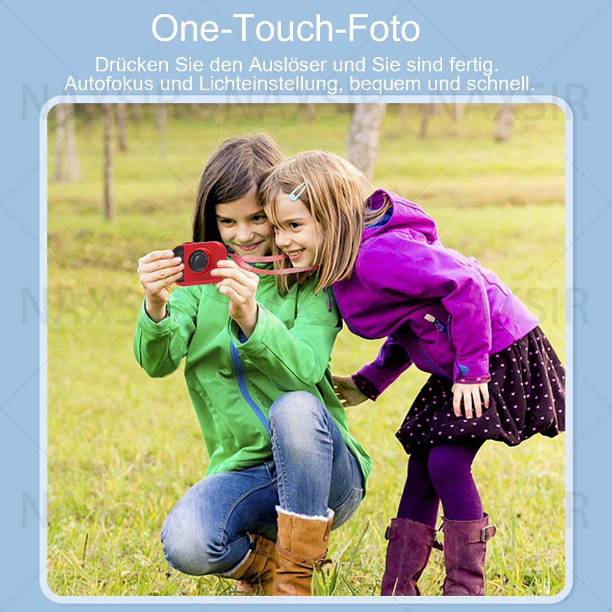 Due ragazze si stanno scattando una foto con una fotocamera rossa per bambini. Una ragazza sta sorridendo. Sono in un'area erbosa.