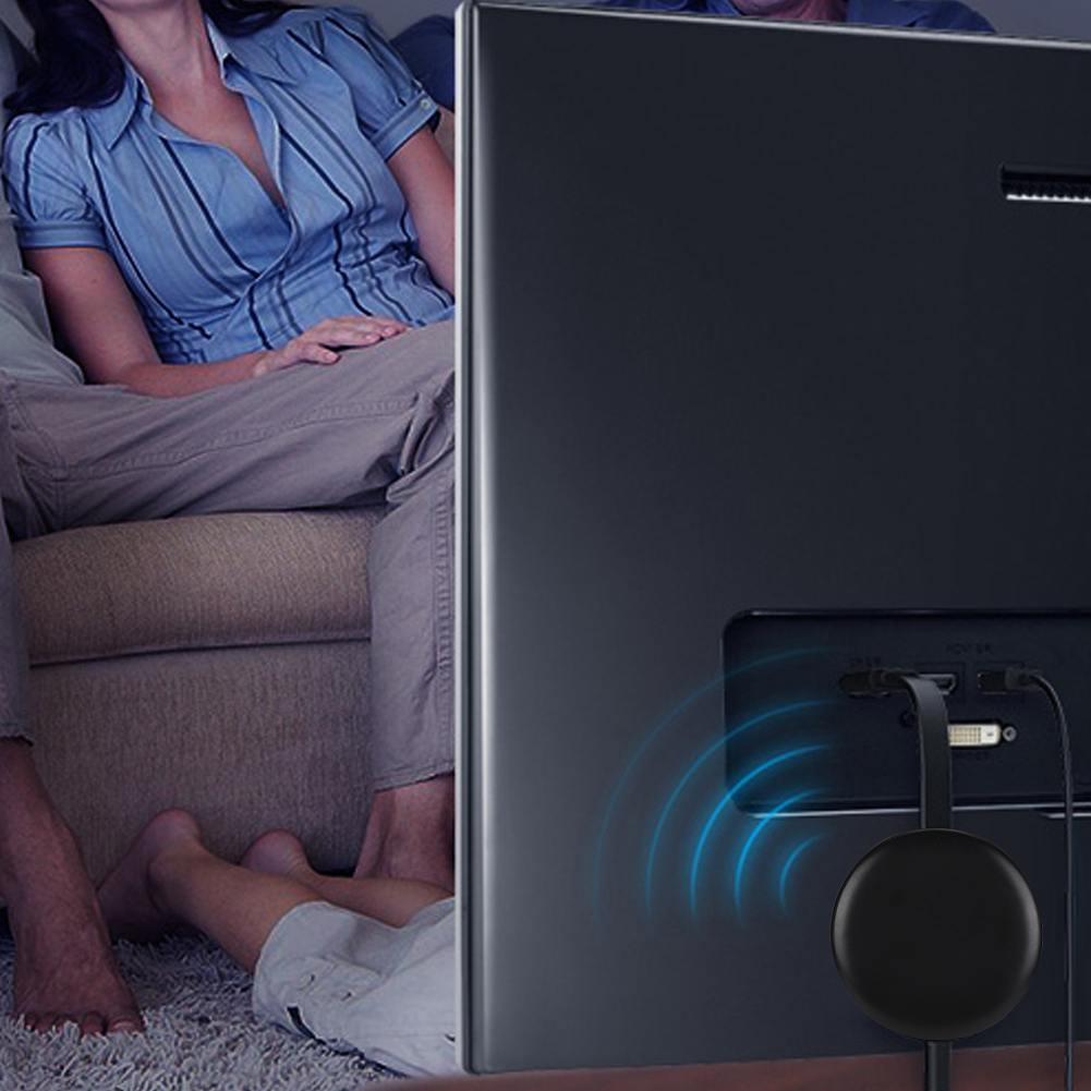 Ein Fernseher ist im Hintergrund. Menschen sitzen auf einem Sofa. Ein schwarzes Gerät ist mit dem Fernseher verbunden.