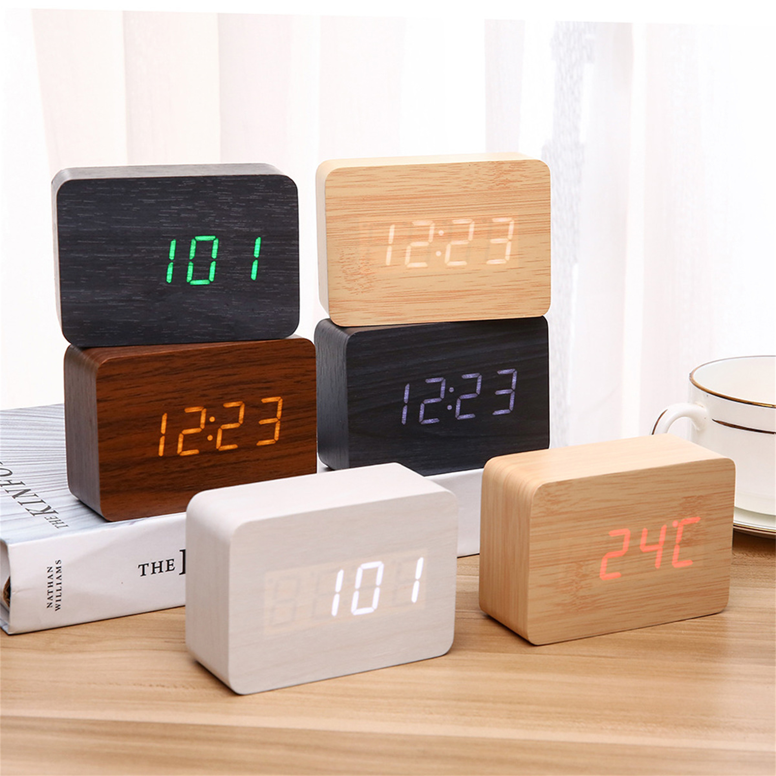 Mehrere Holzuhren auf einem Tisch. Sie zeigen unterschiedliche Zeiten an. Eine zeigt "12:23", eine andere "10:1" usw.