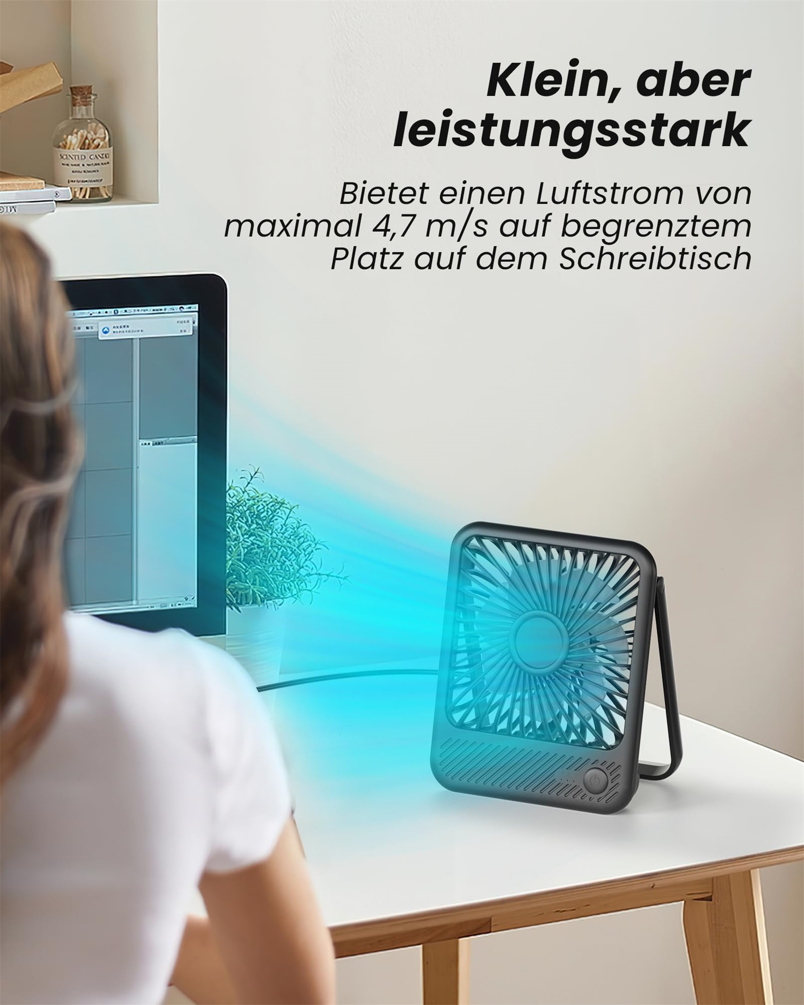 Eine Frau arbeitet am Computer, ein kleiner Ventilator steht auf dem Schreibtisch.
