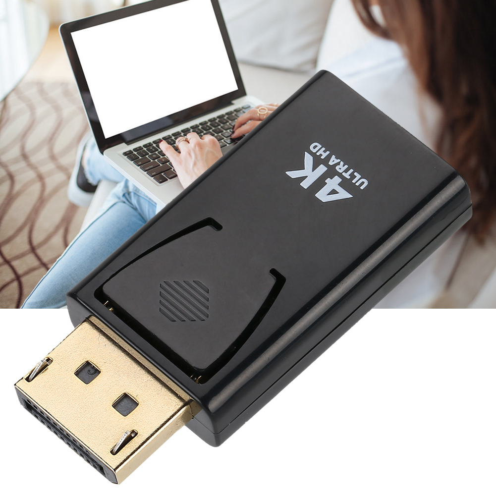 Schwarzer Adapter mit goldenem DisplayPort, beschriftet mit „4K Ultra HD“, Laptop im Hintergrund.