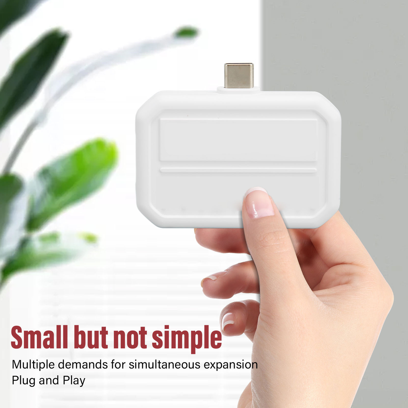 Eine Hand hält einen weißen Adapter. Der Adapter hat einen USB-C-Anschluss. Text lautet: 'Small but not simple'.