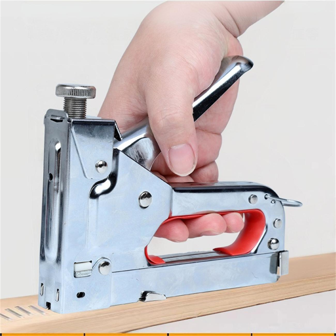 Eine Hand, die eine Tackerpistole auf einem Holzstück verwendet.
