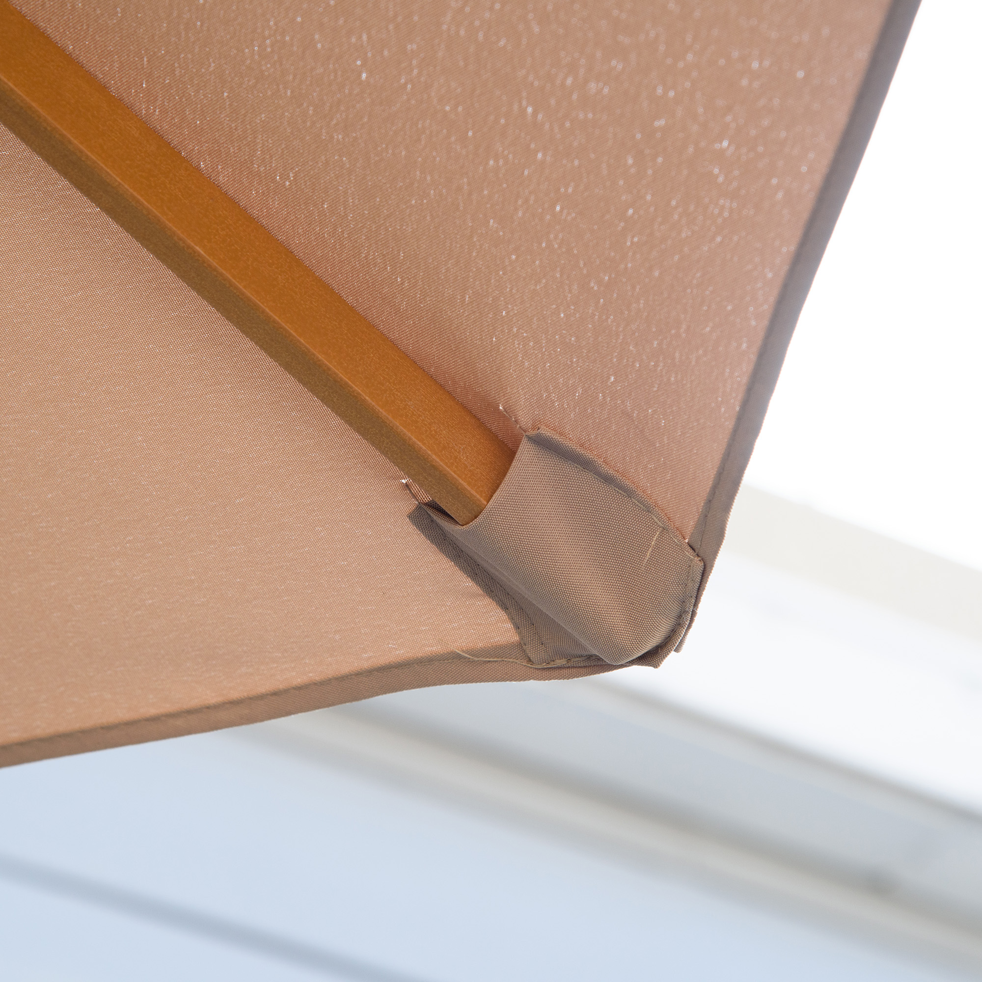 Nahaufnahme eines beigefarbenen Sonnenschirmdachs mit Holzrahmen und braunem Stoffeckdetail.