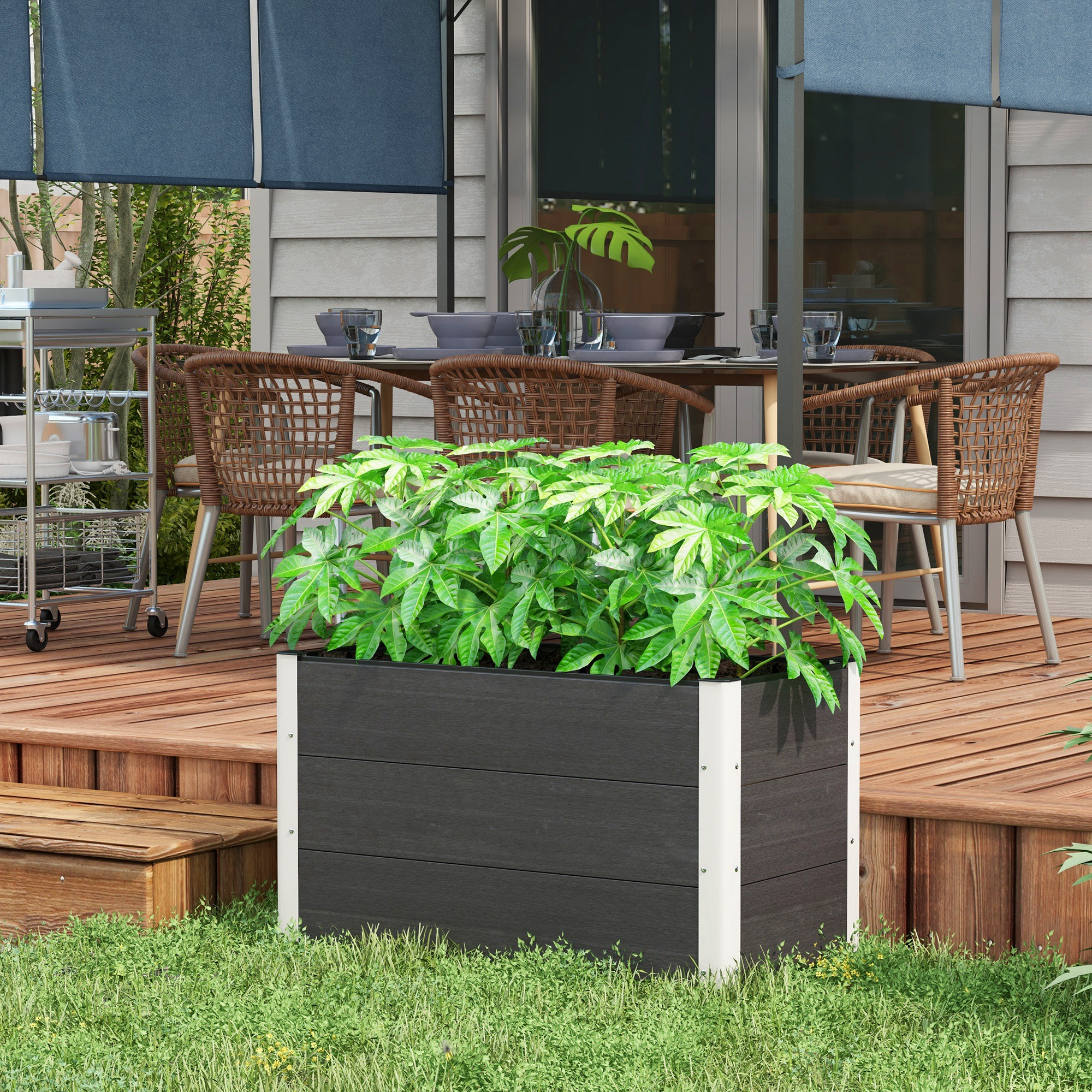 Ein erhöhtes Gartenbeet mit Pflanzen auf einer Holzterrasse mit Gartenmöbeln und blauen Markisen.
