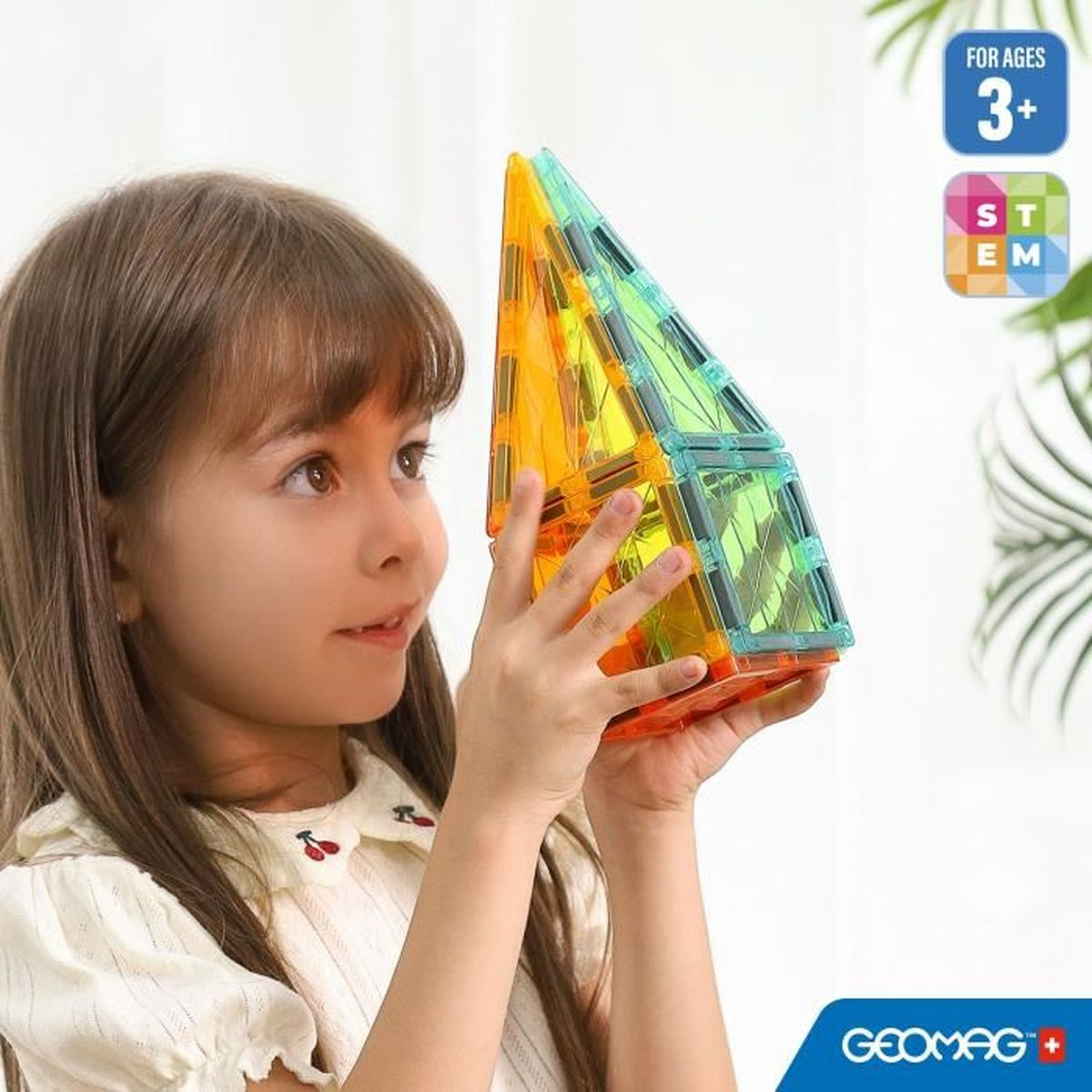 Una bambina che tiene in mano un giocattolo geometrico fatto di forme colorate. Il giocattolo è trasparente e colorato.