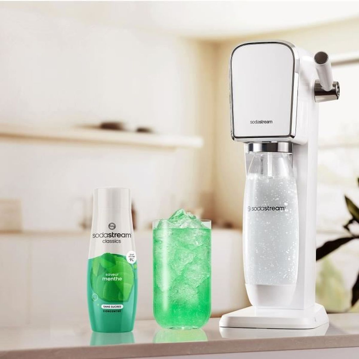 Eine SodaStream-Maschine, ein Glas grünes Getränk und eine Flasche Minz-Aromakonzentrat.