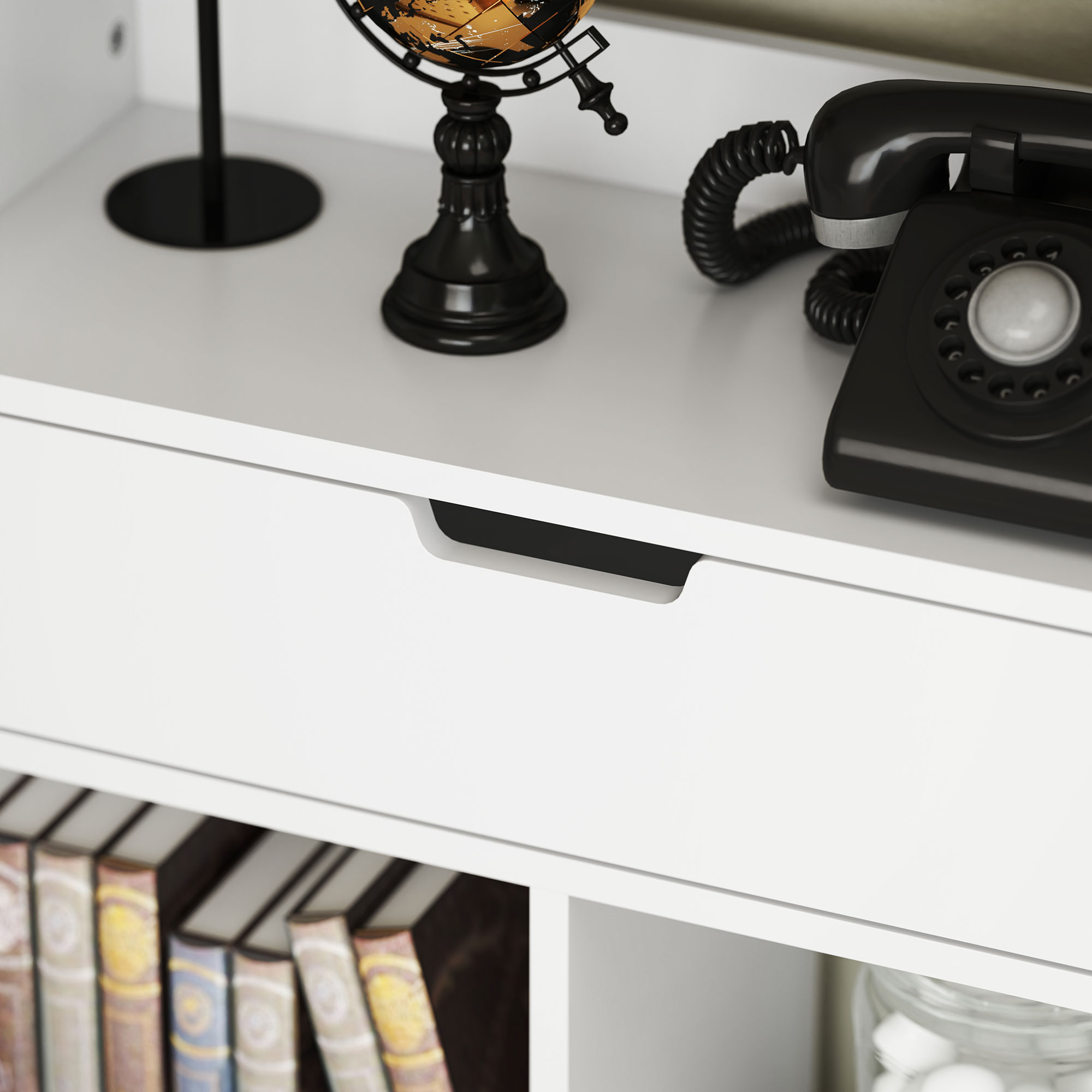 Eine Schreibtischszene mit weißer Schublade, Büchern, Globus und einem schwarzen Wählscheibentelefon.