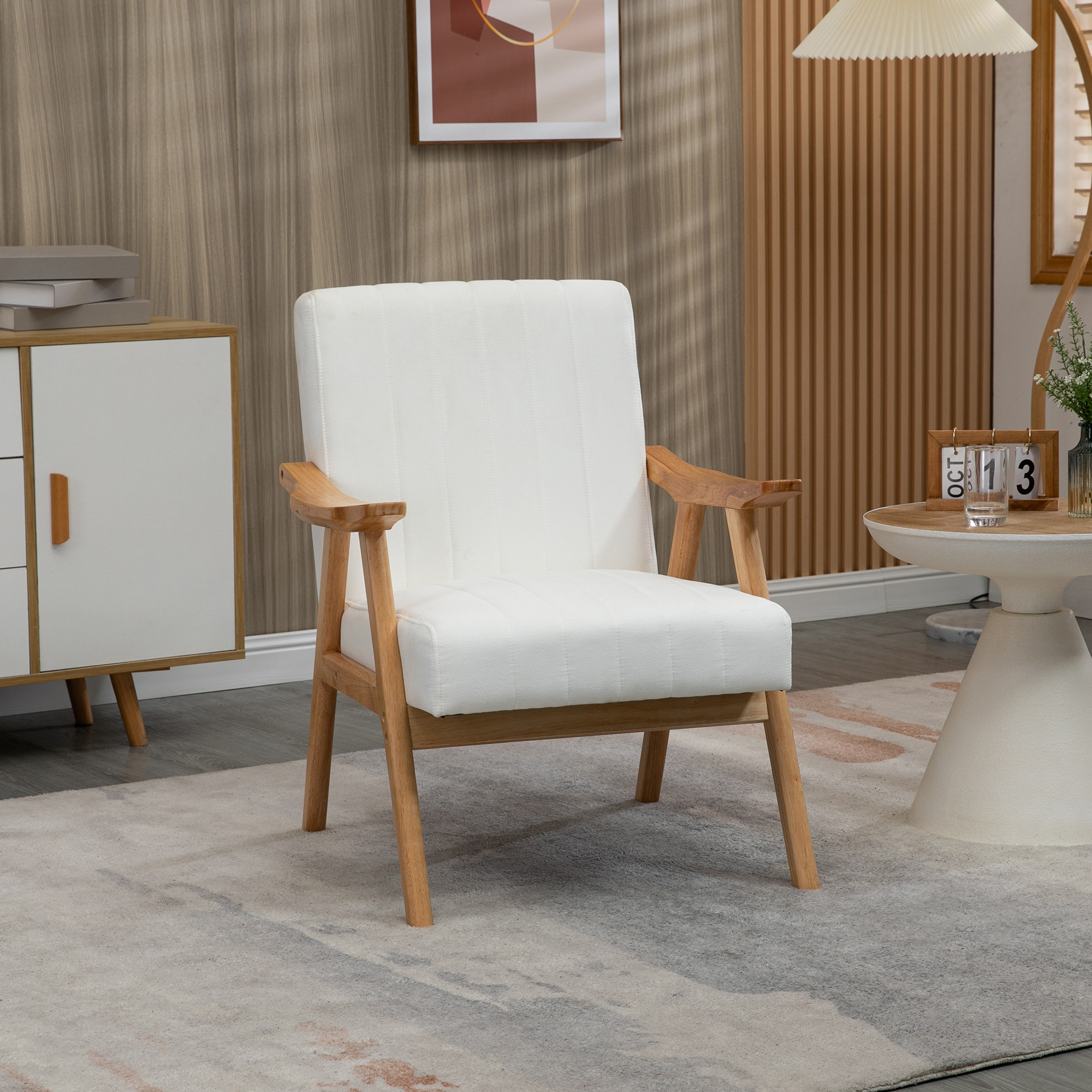 Wohnzimmer mit einem weißen Sessel mit Holzrahmen. Ein runder Tisch und ein weißer Schrank sind im Raum.
