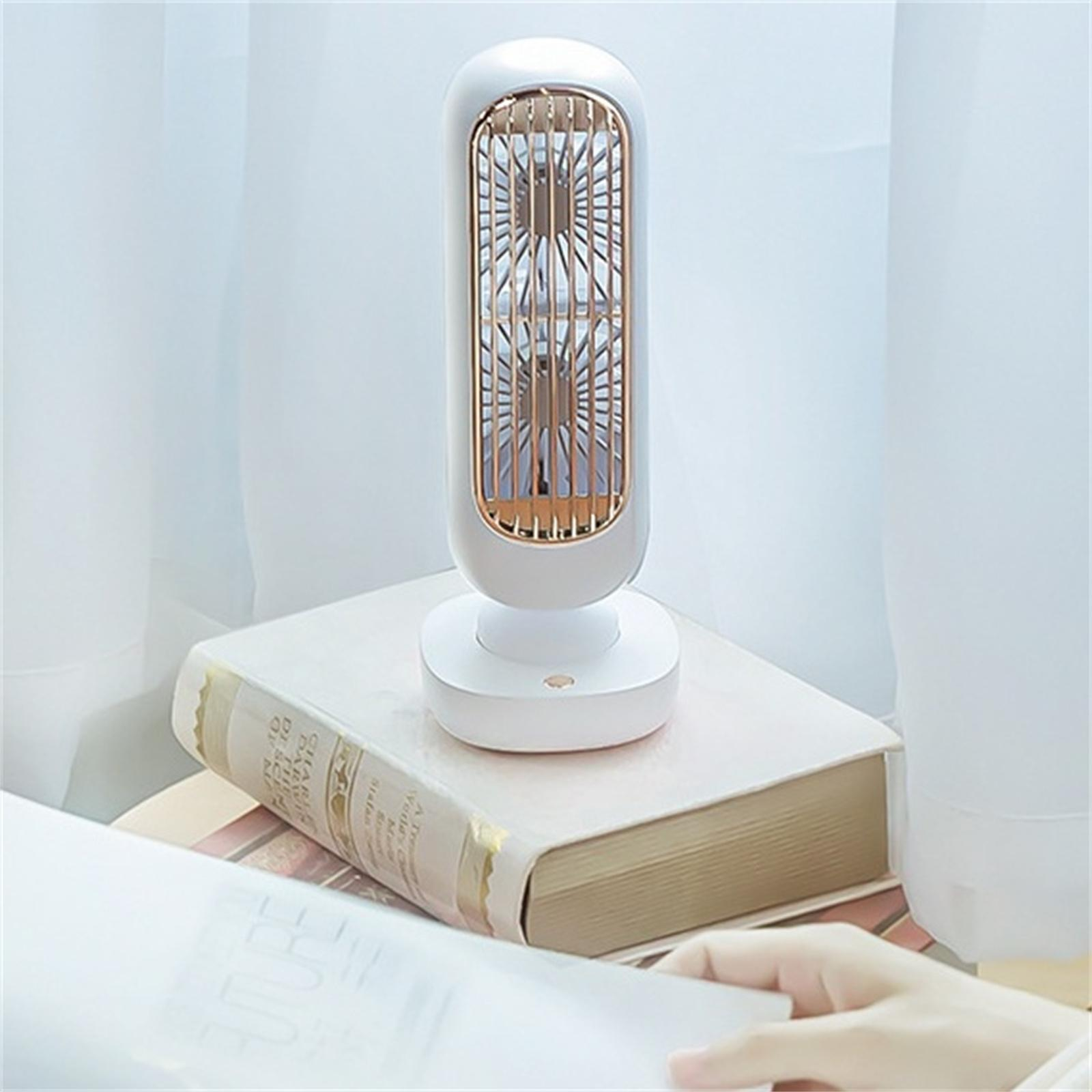 Ein kleiner weiß-goldener Ventilator auf einem Buch. Der Ventilator hat zwei Flügel in einem goldenen Käfig.