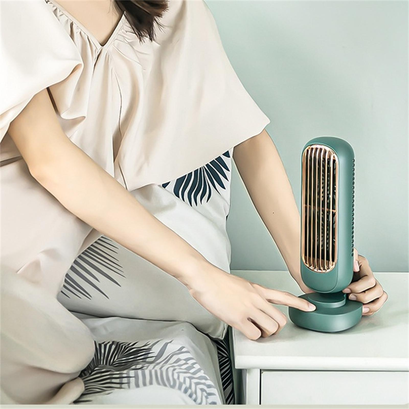 Die Hand einer Person zeigt auf einen grünen Ventilator auf einem Nachttisch.