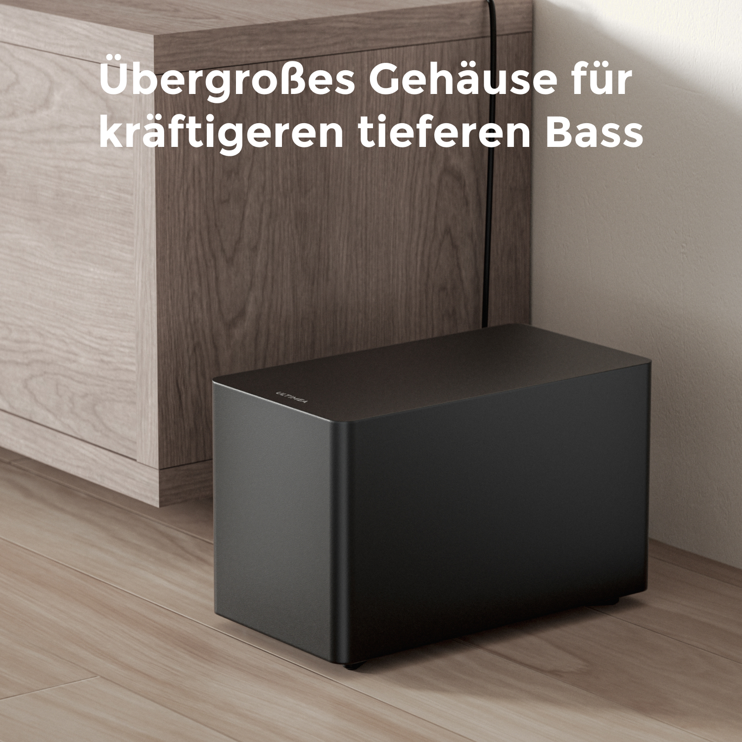 Ein schwarzer Subwoofer auf einem Holzboden neben einem braunen Schrank. Text steht darüber.