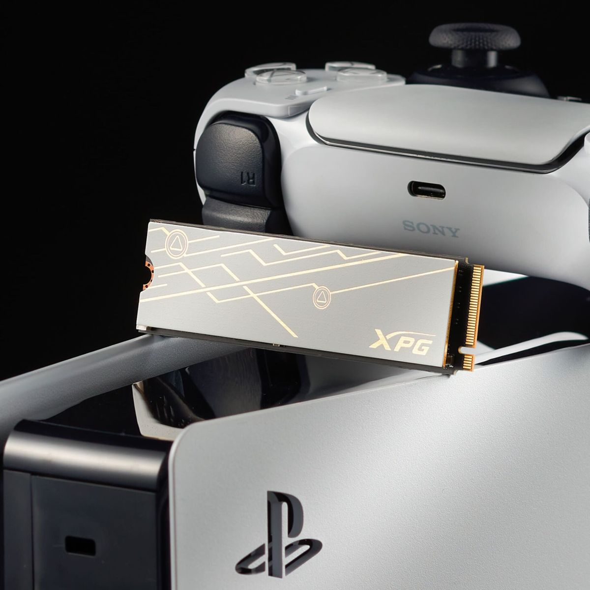 Srebrny dysk SSD z logo XPG, umieszczony na konsoli PlayStation 5 z kontrolerem.