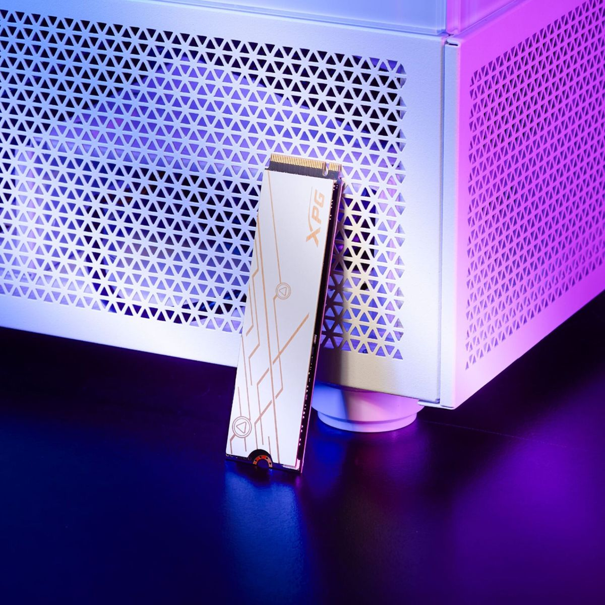 Biały dysk półprzewodnikowy XPG opiera się o białą obudowę komputera PC z niebieskim i fioletowym oświetleniem.