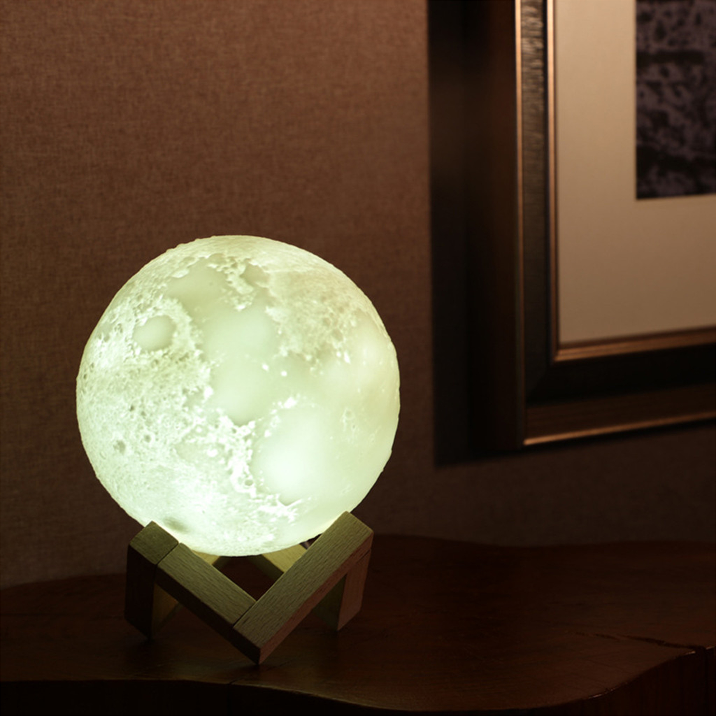 Mondförmige Lampe auf einem Holzständer. Die Lampe leuchtet grün, platziert auf einem dunklen Holztisch.
