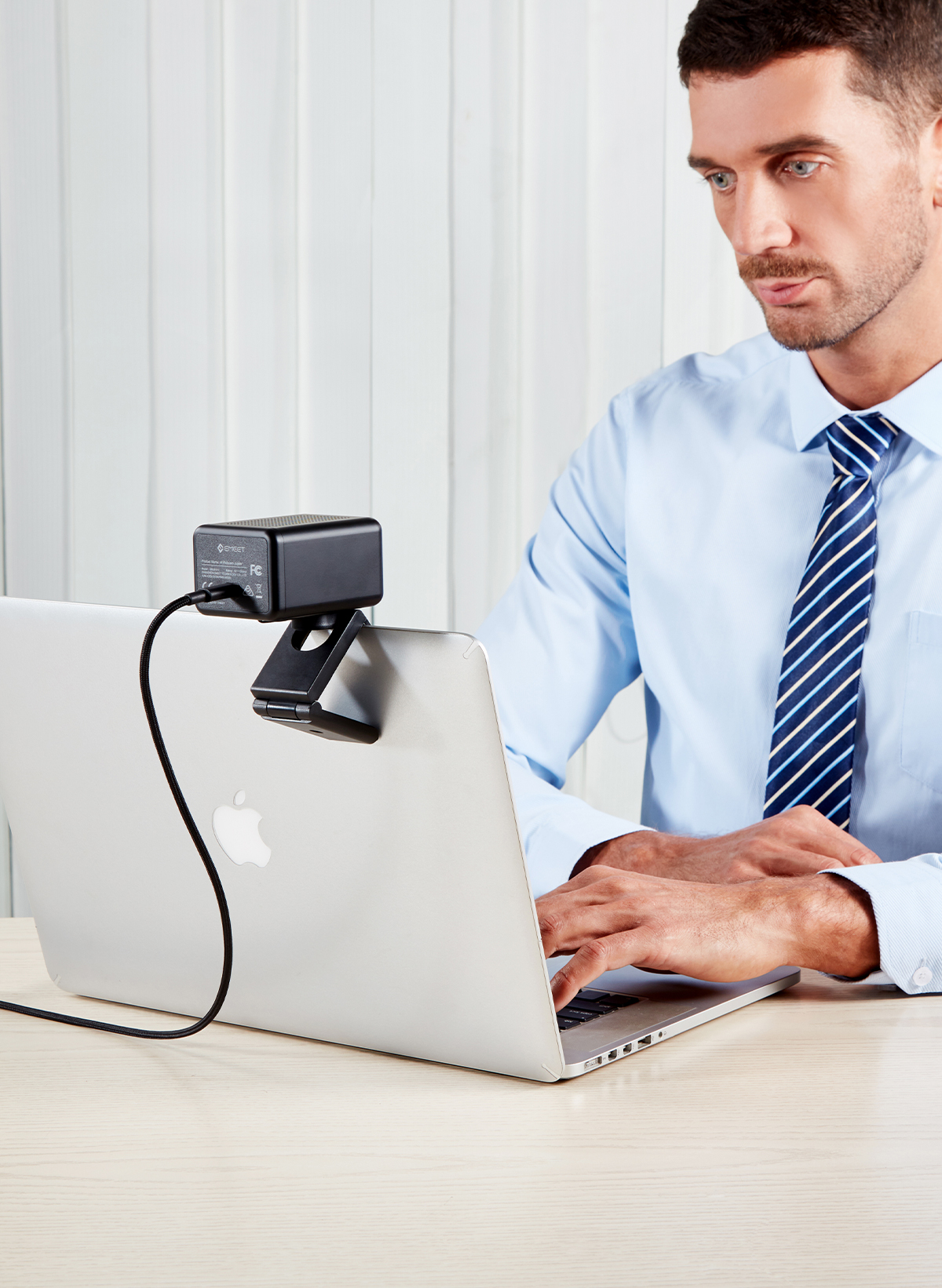 Ein Mann, der einen Laptop mit Webcam benutzt. Der Bildschirm zeigt einen Mann im Anzug.
