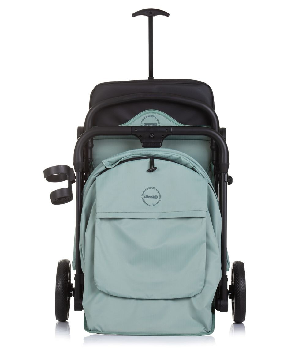 Un cochecito en verde azulado y negro, con asa y portavasos. Tiene una bolsa verde azulado y ruedas negras sobre blanco.