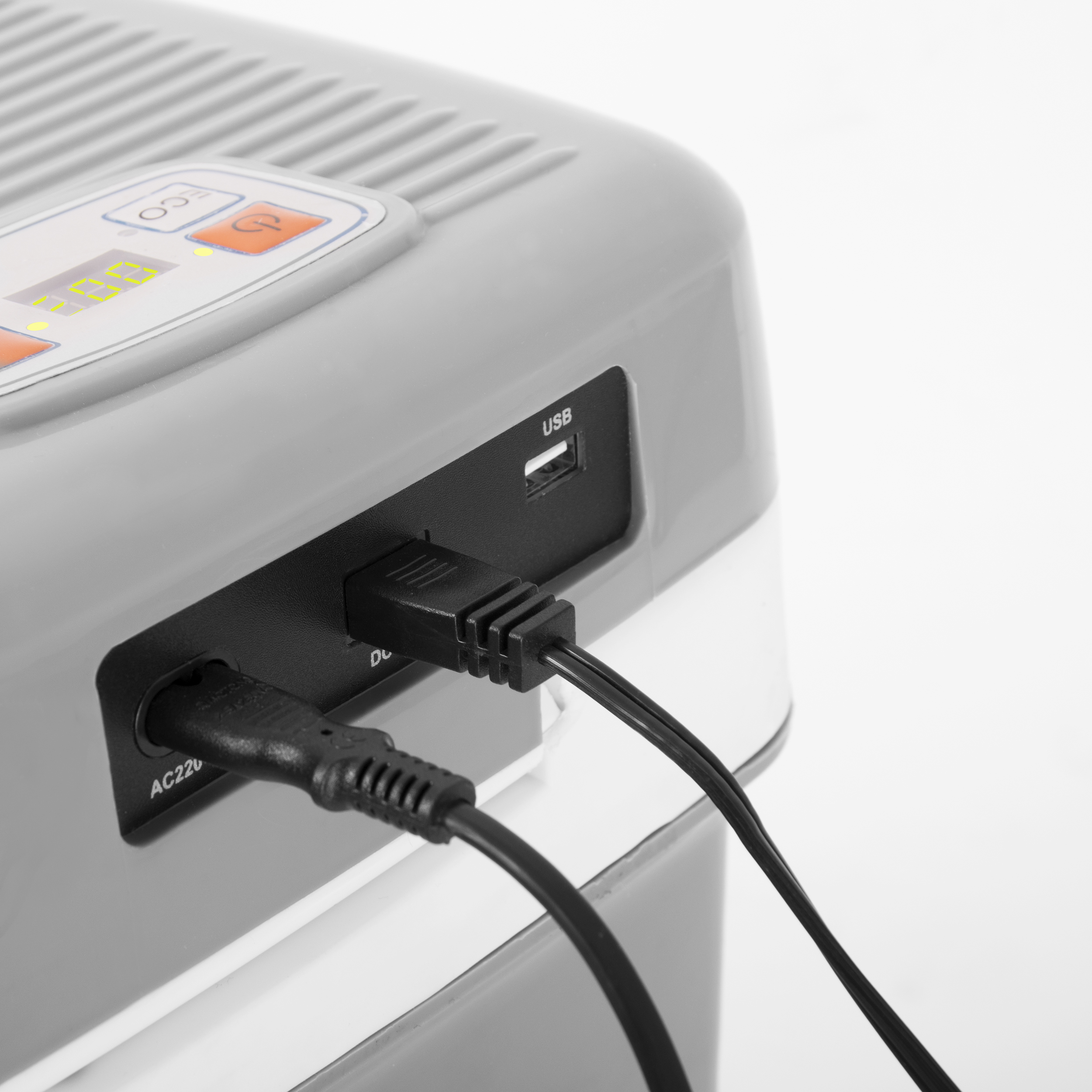 Zbliżenie szarej chłodziarki z wpiętymi czarnymi kablami USB. Widoczne również wejście AC220.