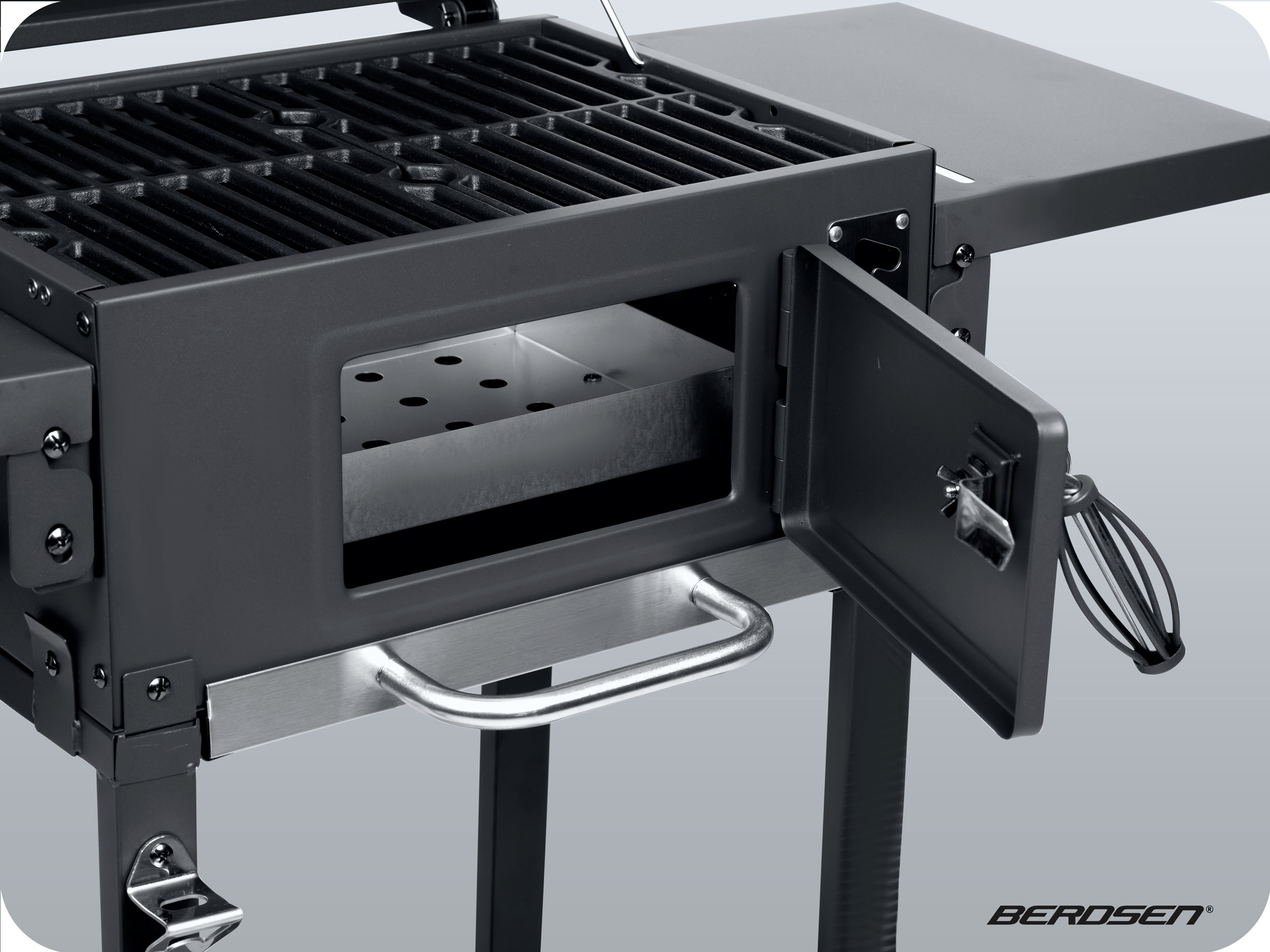 Zbliżenie grilla węglowego z otwartymi drzwiami. Tło jest jasnoszare.