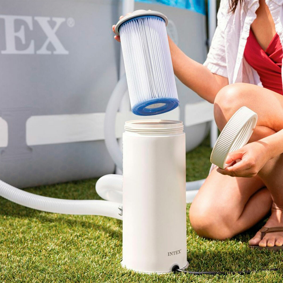 Osoba wyjmuje filtr z białego cylindrycznego urządzenia. Widoczna jest marka INTEXT.