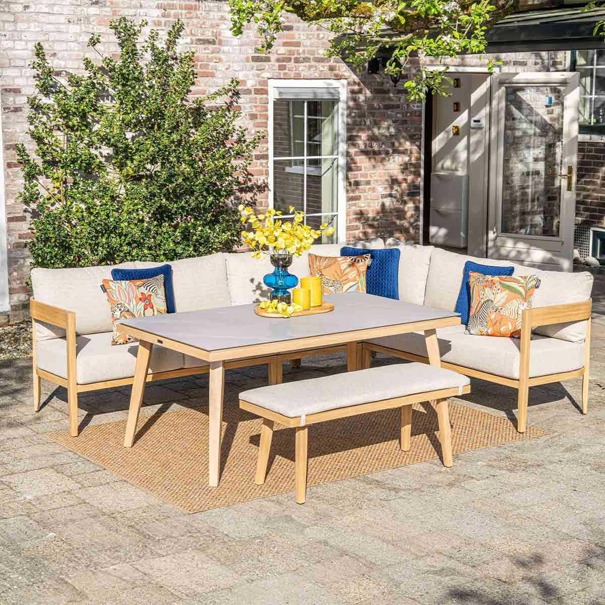 Buitenhoekbank met tafel, bank en kussens. Beige kussens, houten frame.