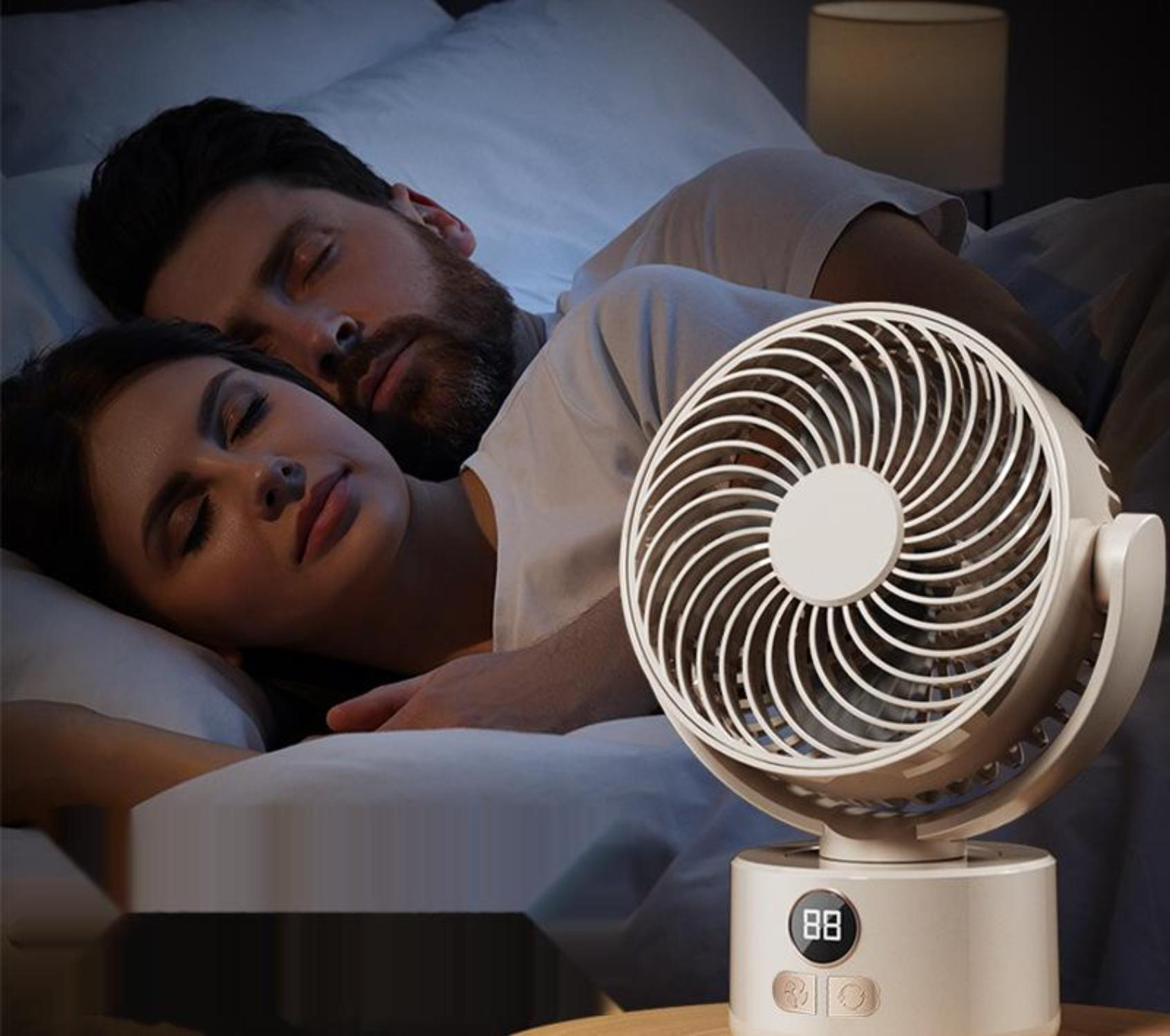 Ein Paar schläft im Bett mit einem weißen Ventilator auf einem Nachttisch.