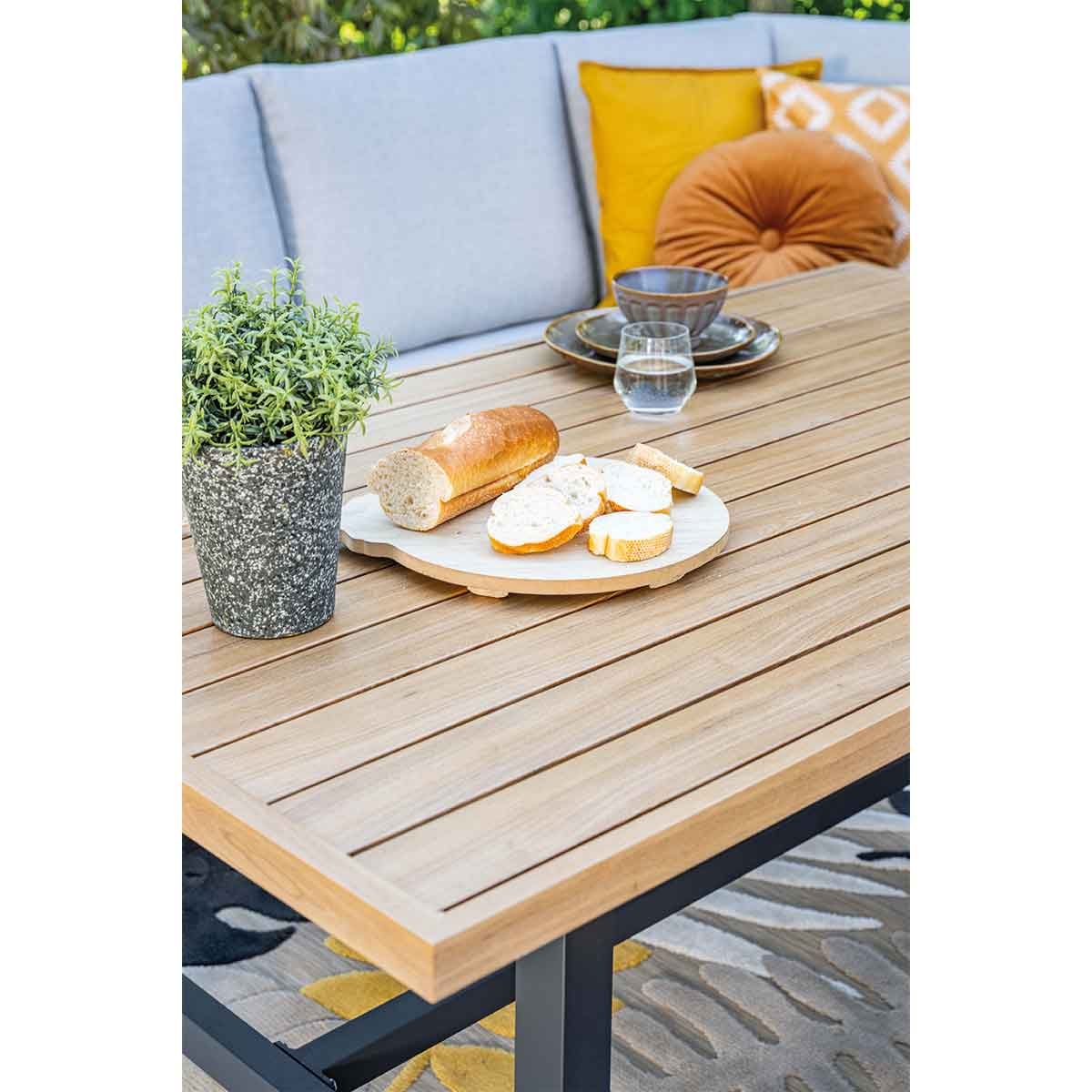 Gros plan sur des aliments et des boissons sur une table en bois. Des assiettes, du pain et un verre d'eau sont visibles.