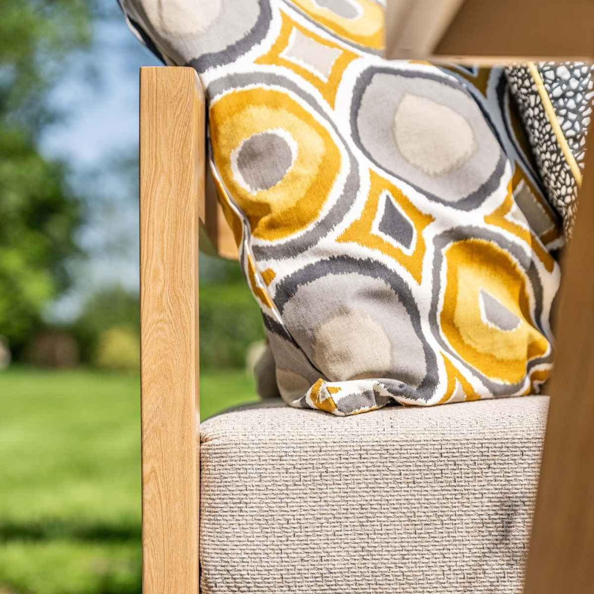 Gros plan sur une chaise avec un coussin à motifs de formes jaunes, grises et blanches.