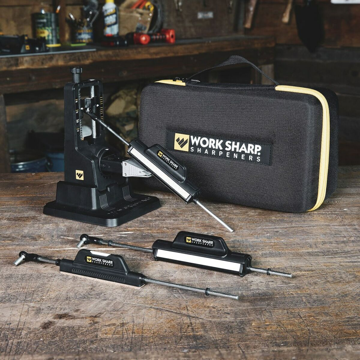 Ein Holztisch mit einem schwarzen Messerschärfer-Kit, Zubehör und einem Koffer. Werkstatt-Hintergrund.