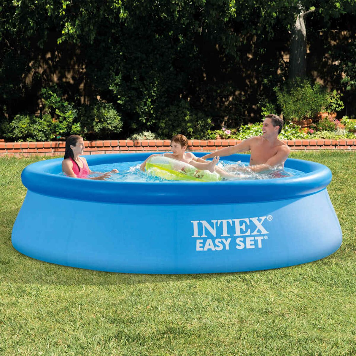 Una familia de tres está en una piscina inflable azul en un patio trasero con césped.