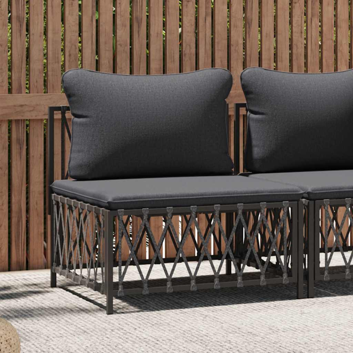 Outdoor-Sofa mit zwei Kissen. Die Basis hat ein gewebtes Design. Der Hintergrund ist ein Holzzaun.