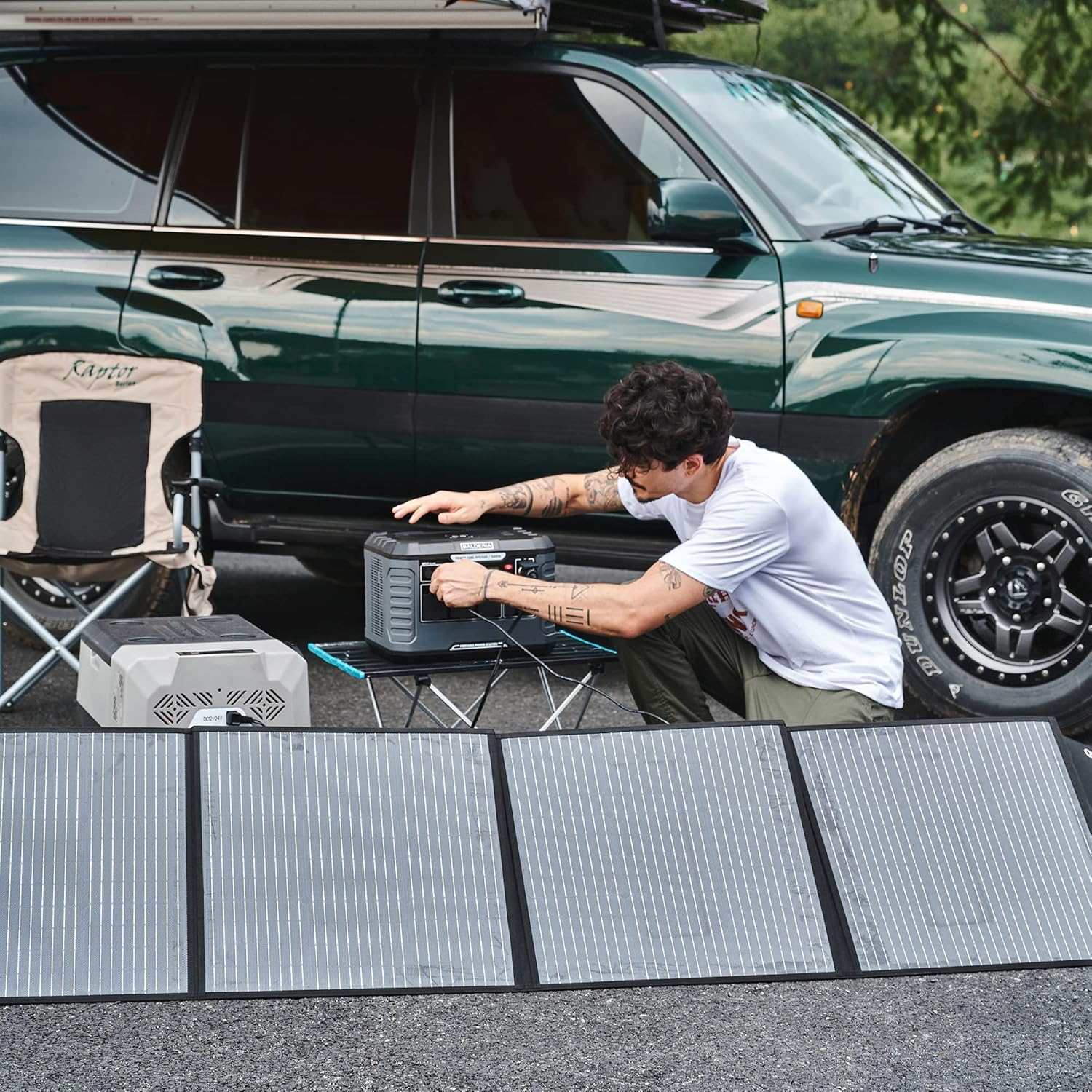 Ein Mann hockt sich und verbindet ein Solarpanel mit einer Stromversorgung neben einem Auto.