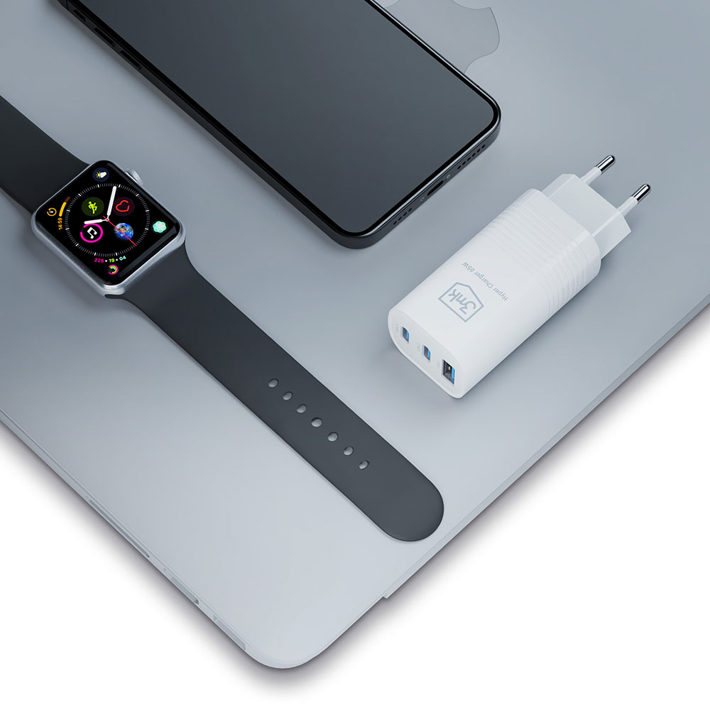 Smartwatch, telefon i ładowarka leżą na laptopie. Wszystkie elementy są na białym tle.