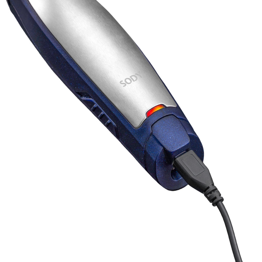 Un trimmer Sody blu e argento con un cavo USB collegato. Una luce rossa indica che il trimmer è in carica.