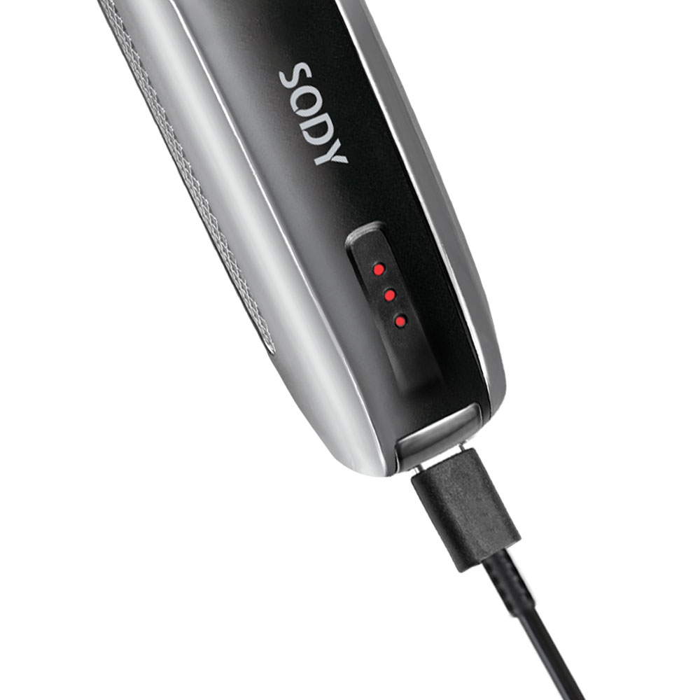 Primo piano di un trimmer Sody nero in carica con un cavo USB. Tre luci rosse indicano lo stato di carica.