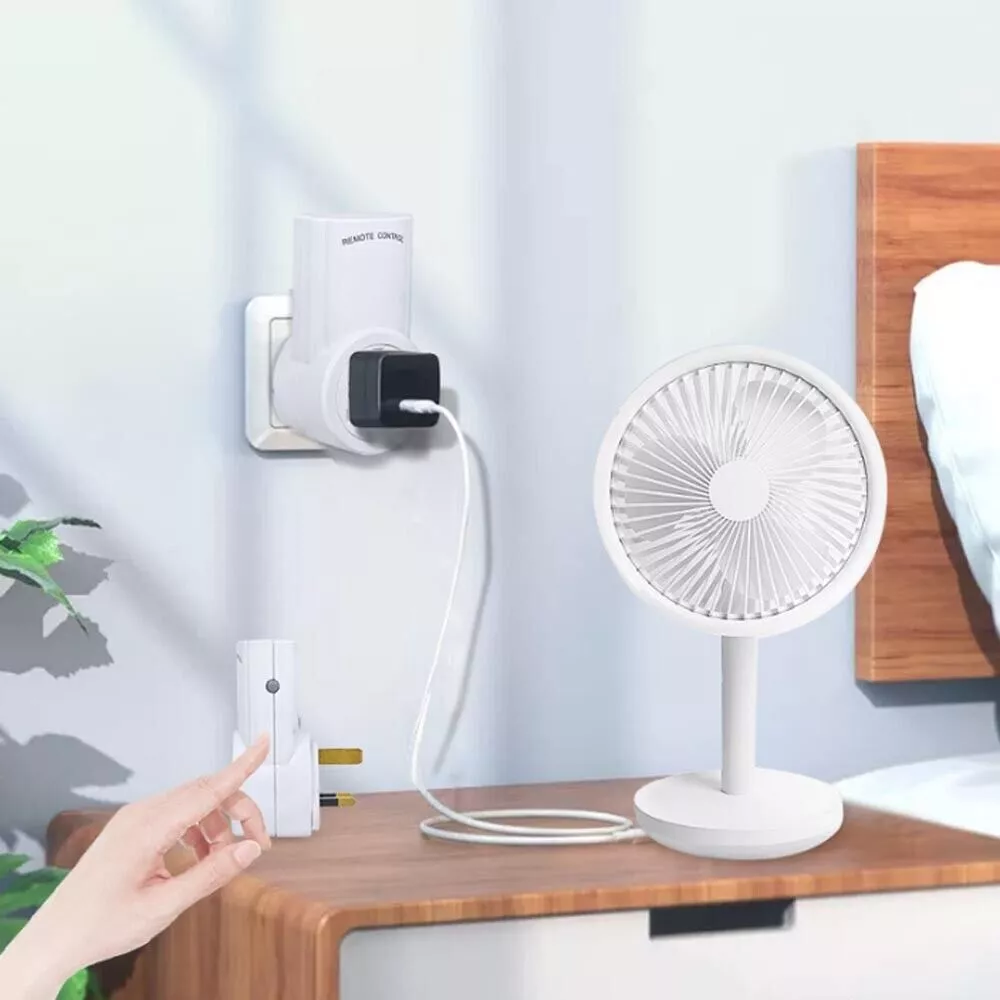 Ein kleiner weißer Ventilator auf einem Ständer, der an eine Steckdose mit einem Fernbedienungsladegerät angeschlossen ist.