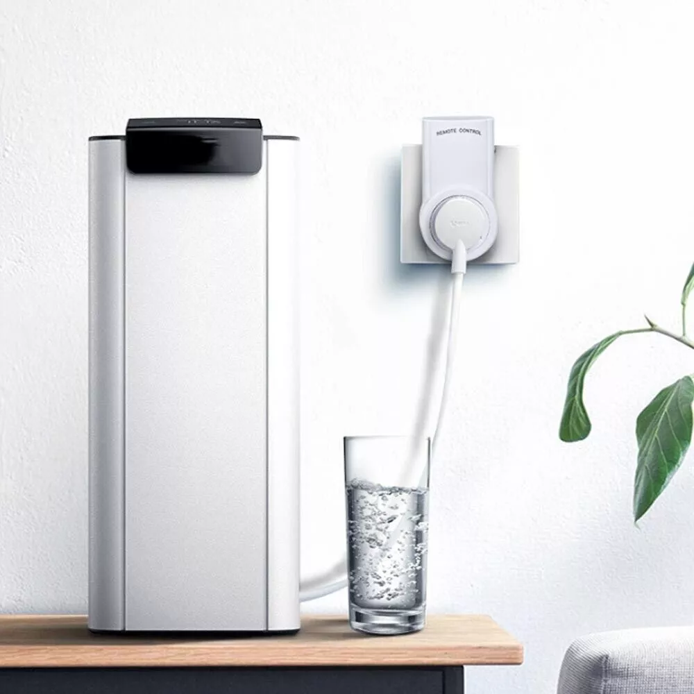 Ein Wasserfilter, ein Glas Wasser und eine Fernbedienungssteckdose an einer Wand.